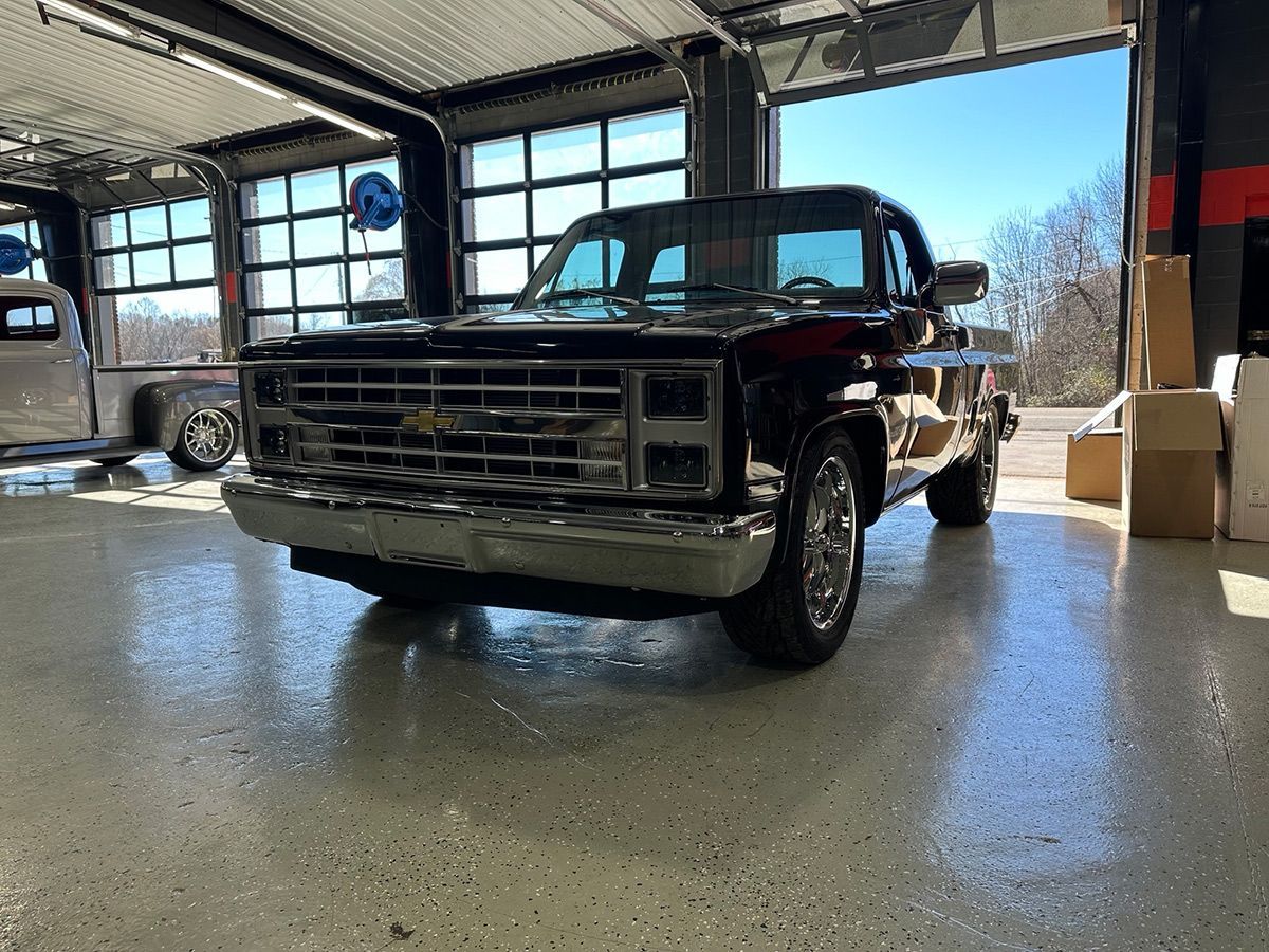 A black Chevrolet truck is parked in a garage.