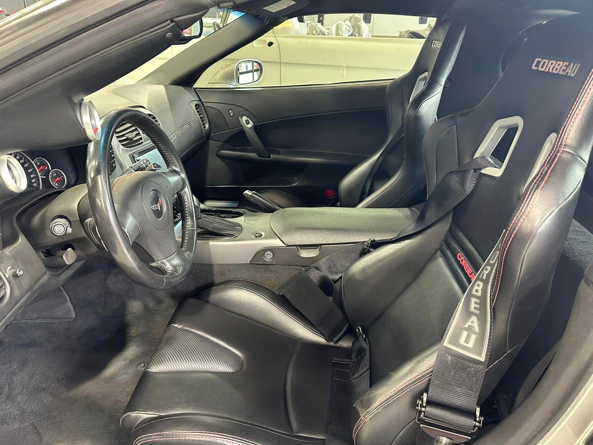 The interior of a sports car with black seats and a steering wheel.