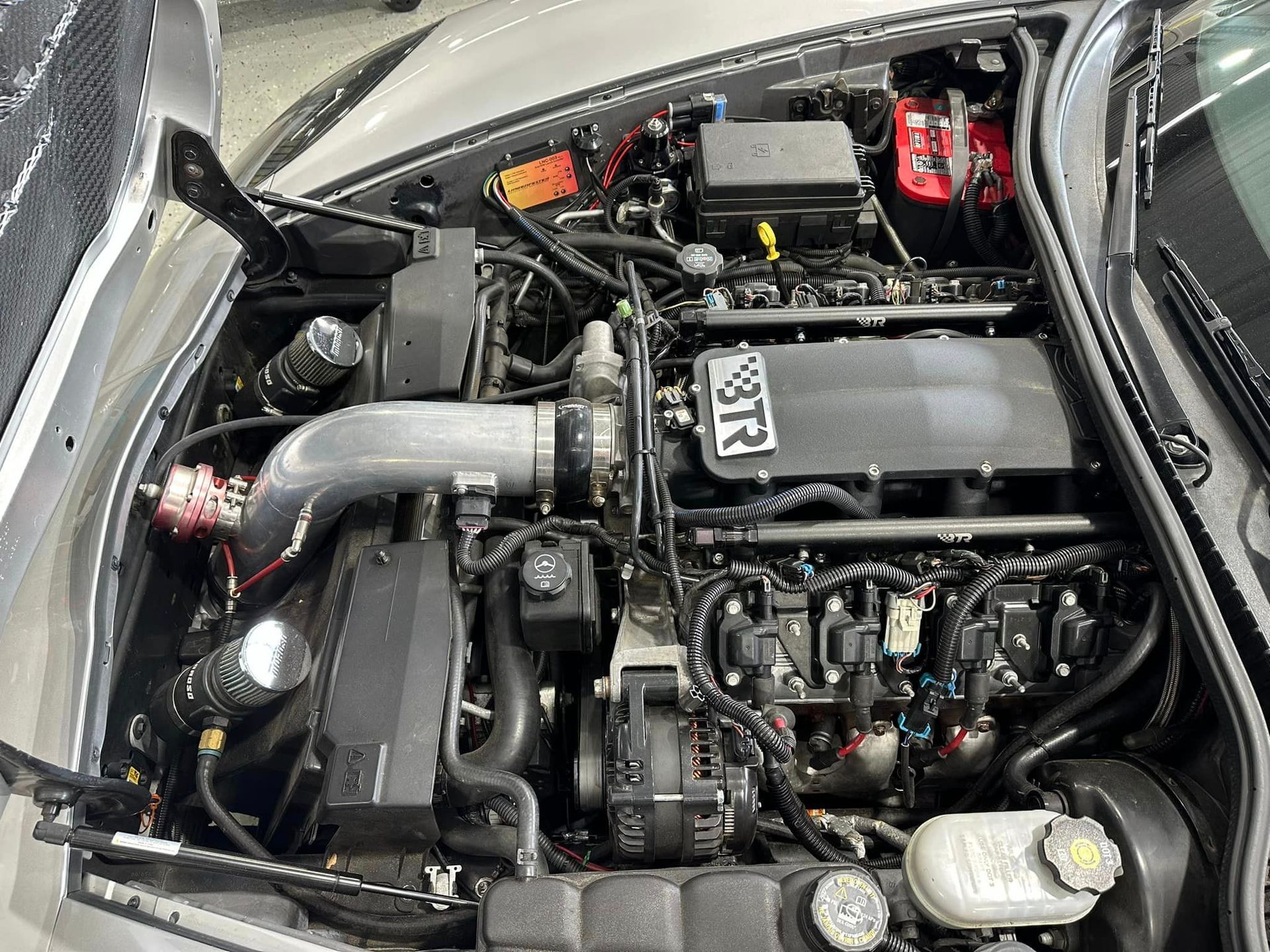 A close up of the engine of a car with the hood open.