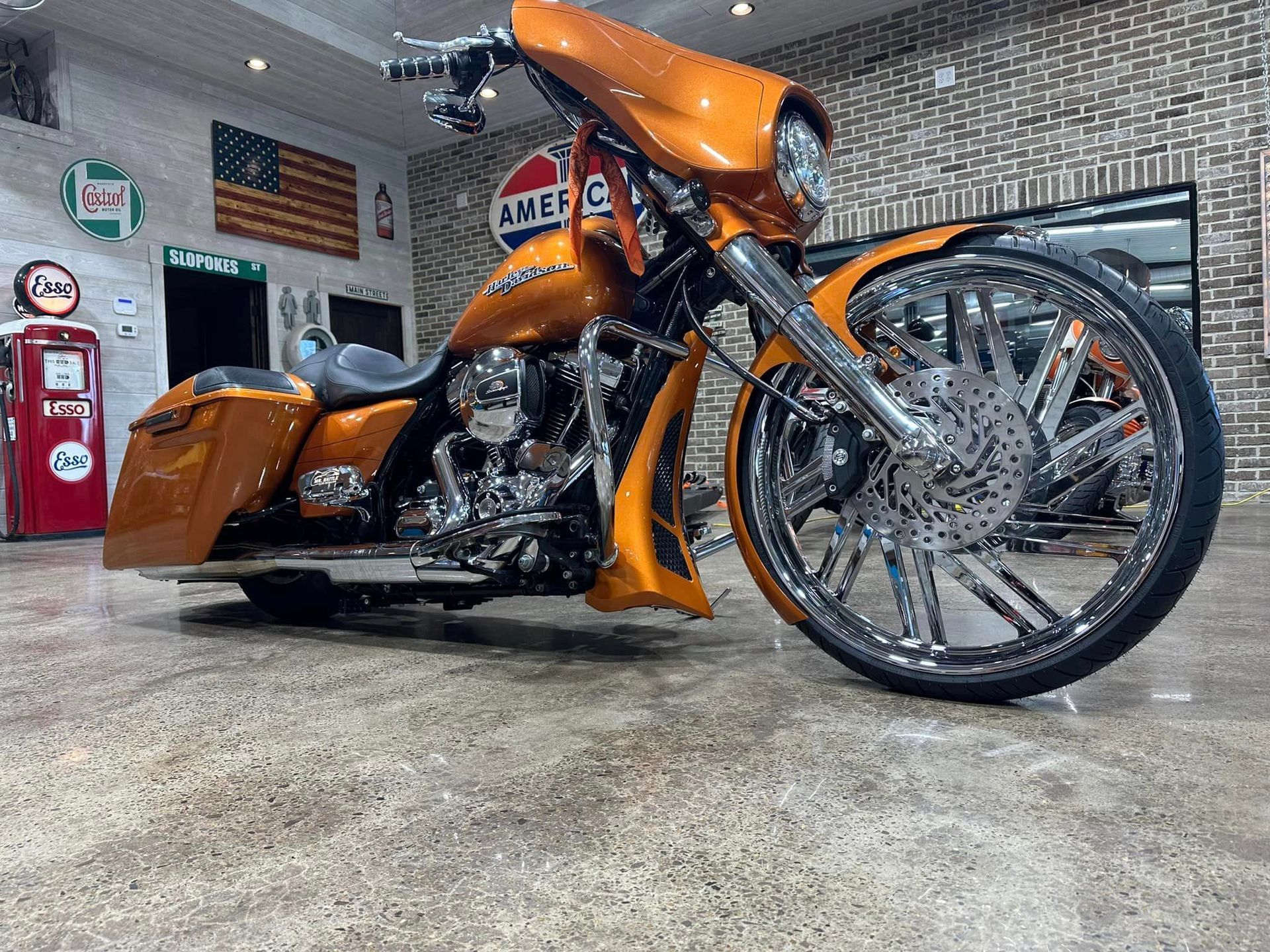 An orange harley davidson motorcycle is parked in a garage.