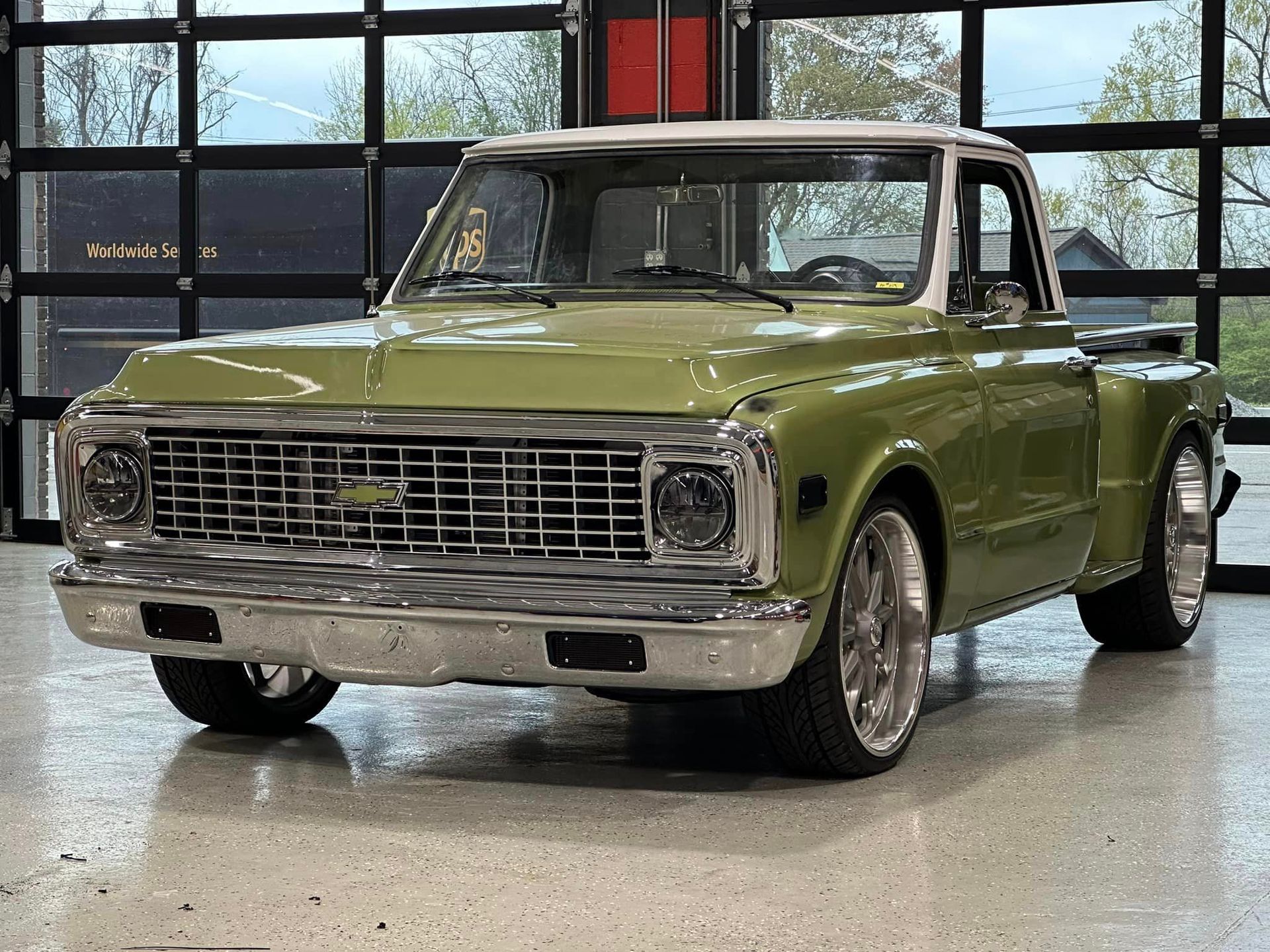 A green chevrolet truck is parked in a garage.