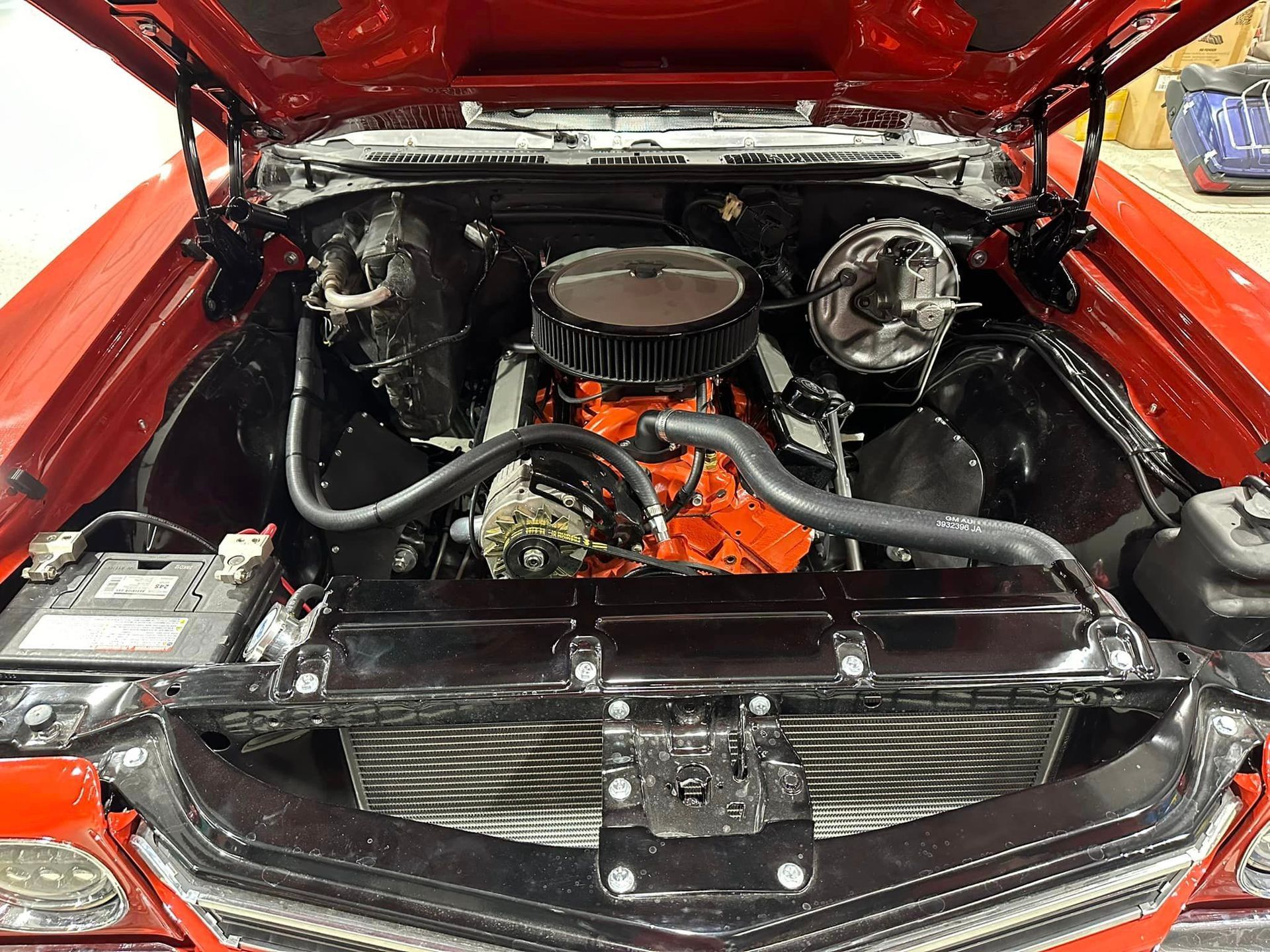 The engine of a red car is shown with the hood open