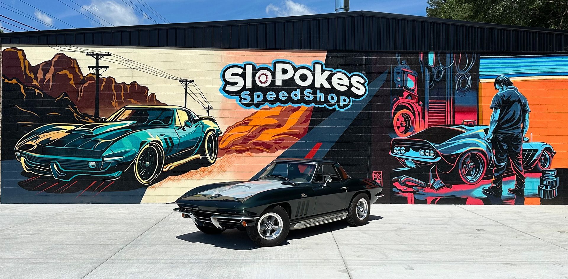 A car is parked in front of a mural on the side of a building.