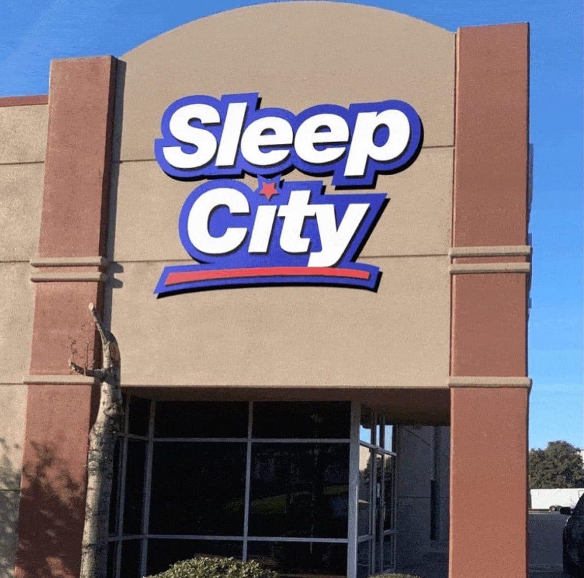 Sleep City store sign on a beige and red building facade