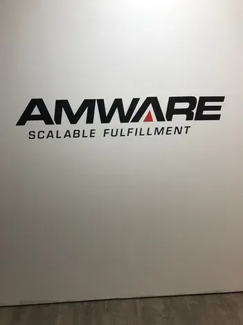 AMWARE logo with “Scalable Fulfillment” on a white wall