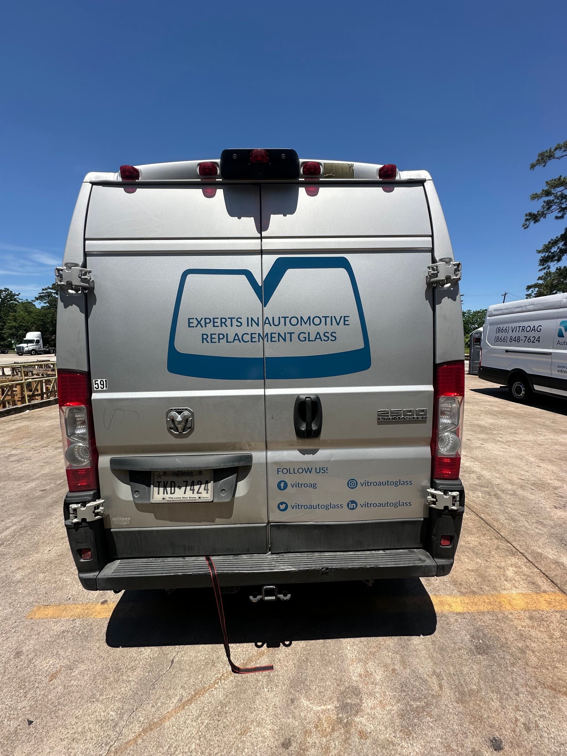 White delivery van with blue logo, parked in a sunny lot