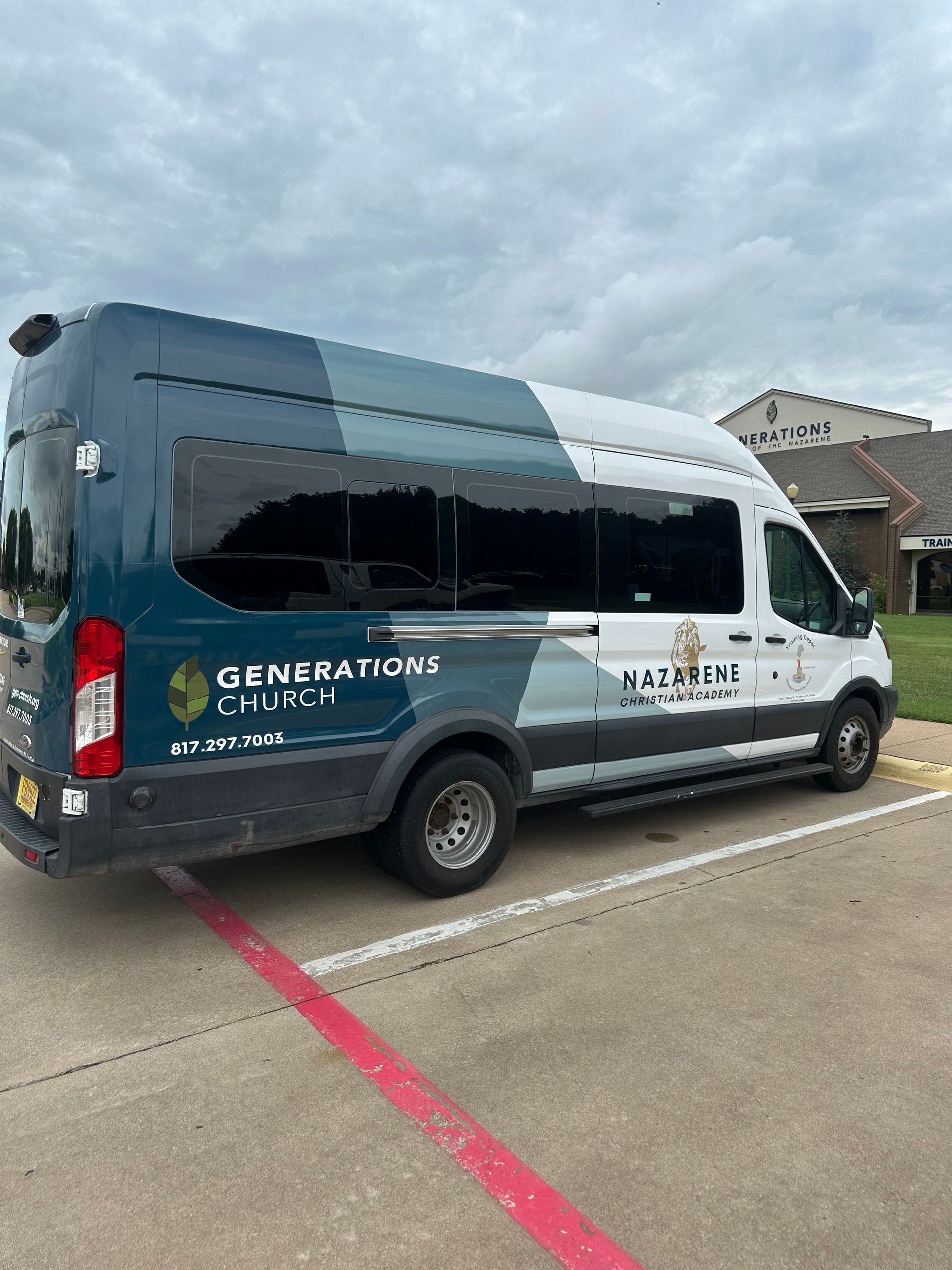 White and navy shuttle van parked in a lot with Generations Auto Care branding on the side