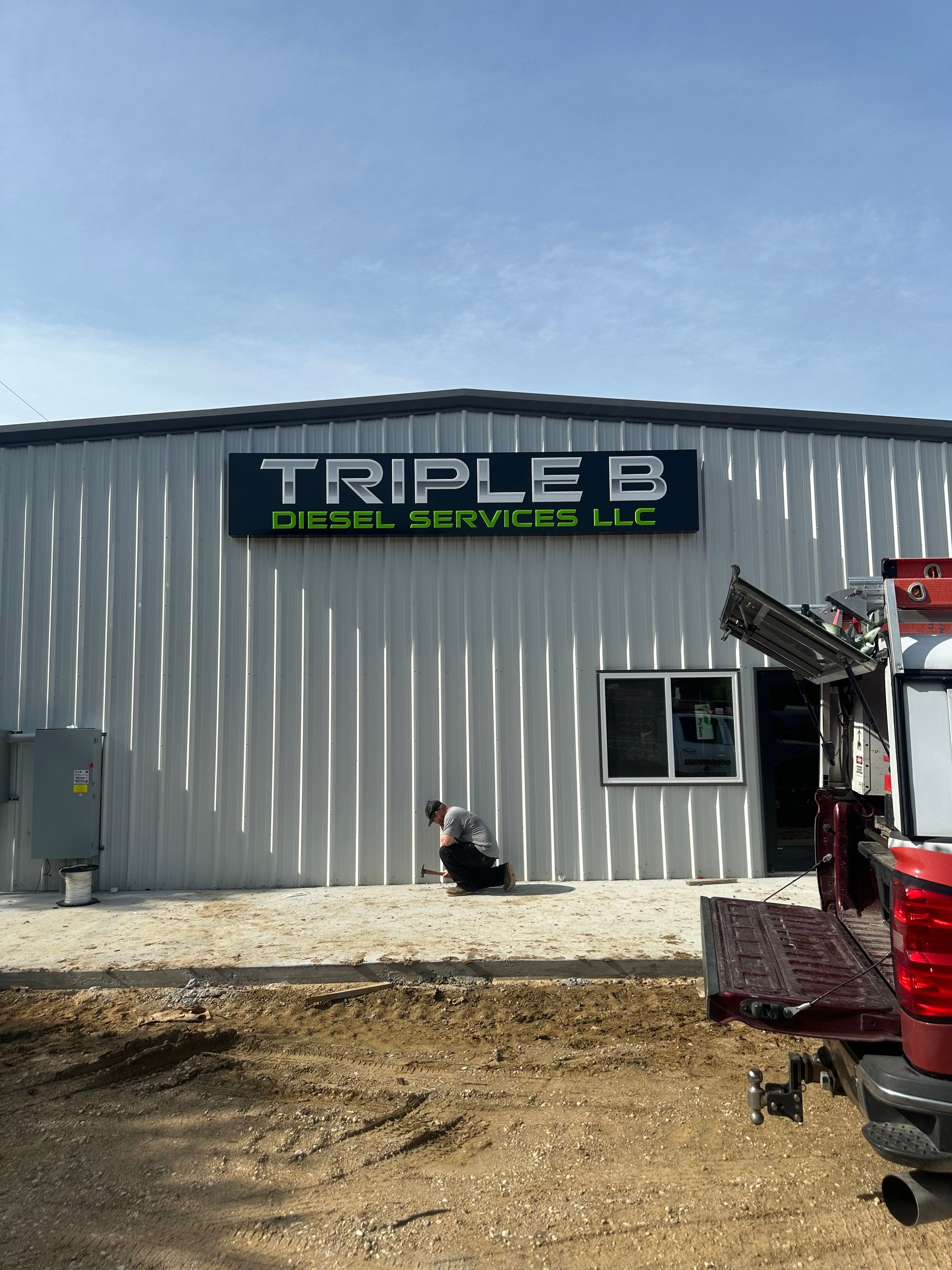 Triple B Diesel Services LLC building with a sign, gravel lot, and a red truck at the right edge