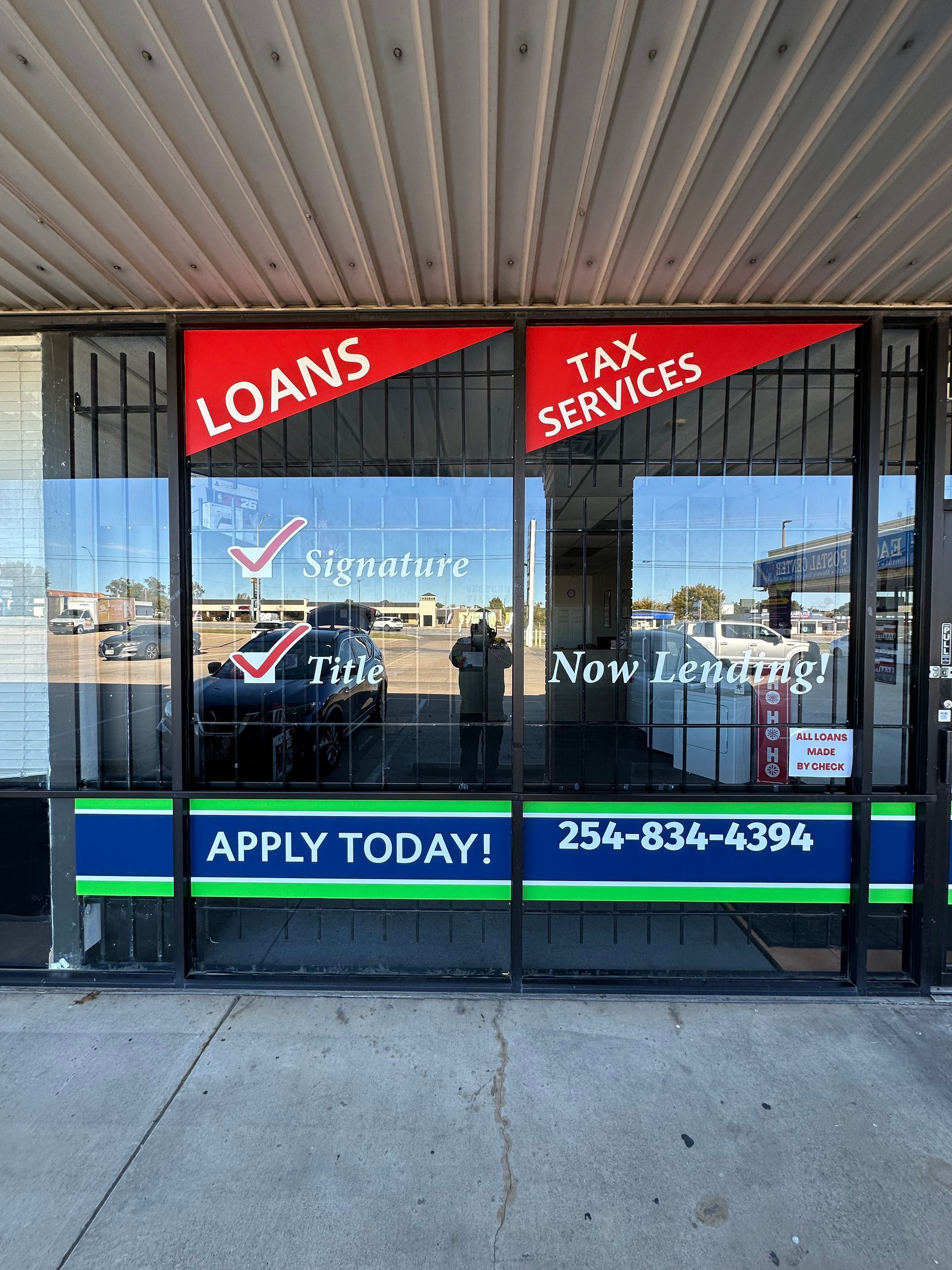 Storefront window advertising loans and tax services, with “Apply Today!” and a phone number.