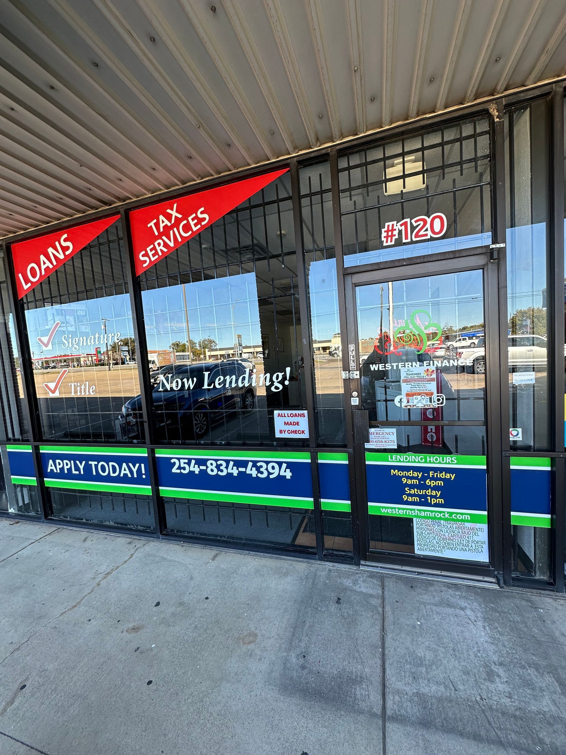 Storefront with glass doors, red loan and tax service signs, and blue-green trim under an awning