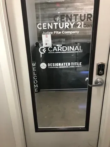 Glass office door with business logos and vertical “WELCOME” lettering