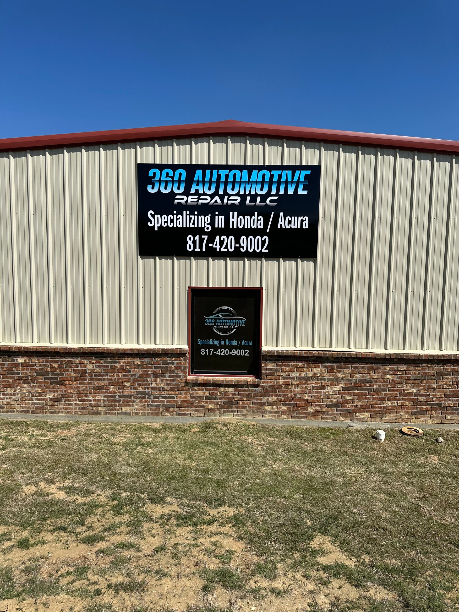 3D Automotive Repair sign on a metal building with red roof, blue sky, and patchy grass foreground