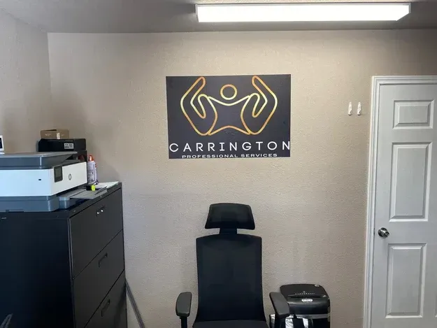 Treatment room with exam chair, printer, and Carrington wall sign
