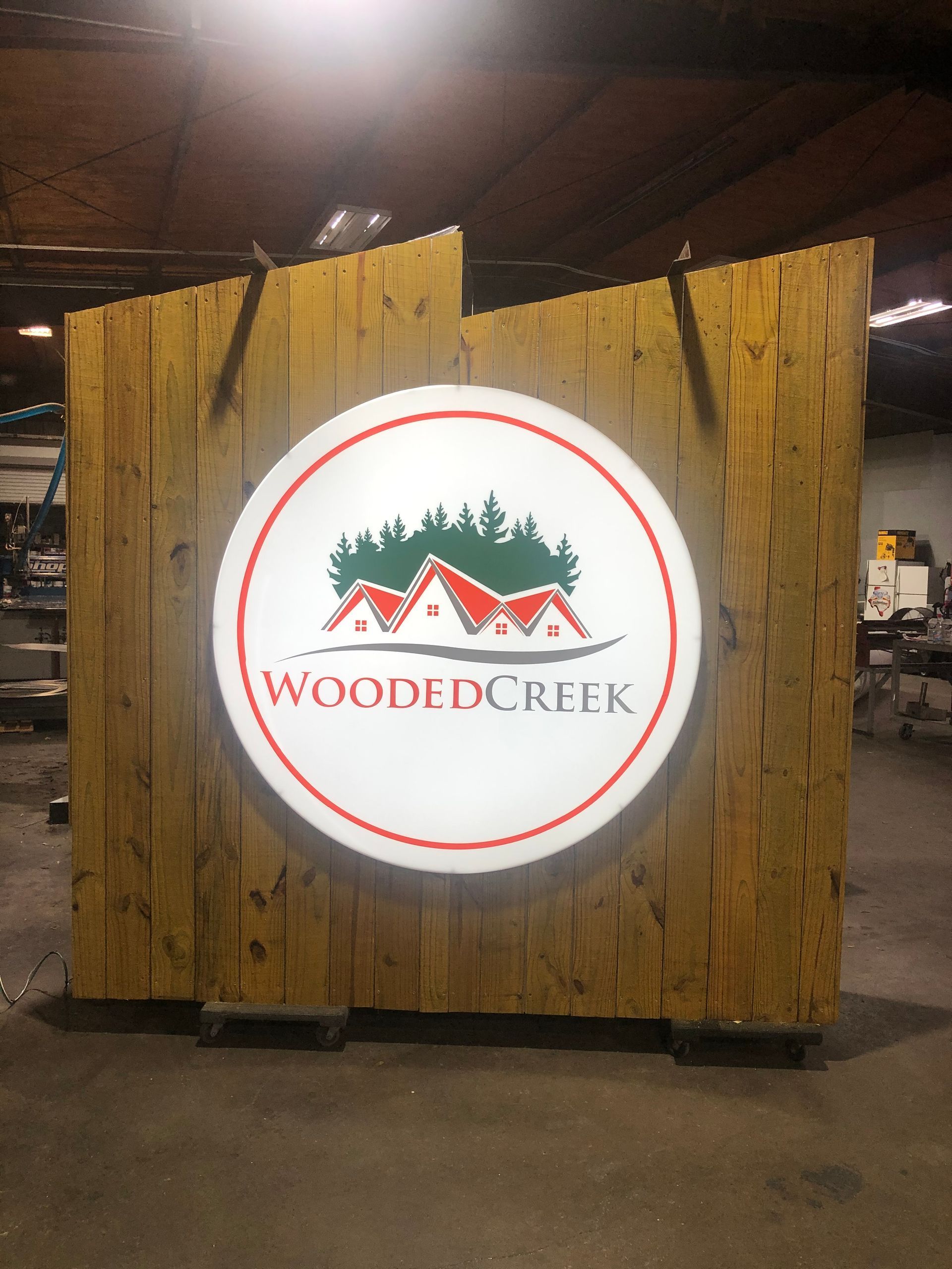 Wooden sign with a round Wooded Creek logo in a dim indoor setting
