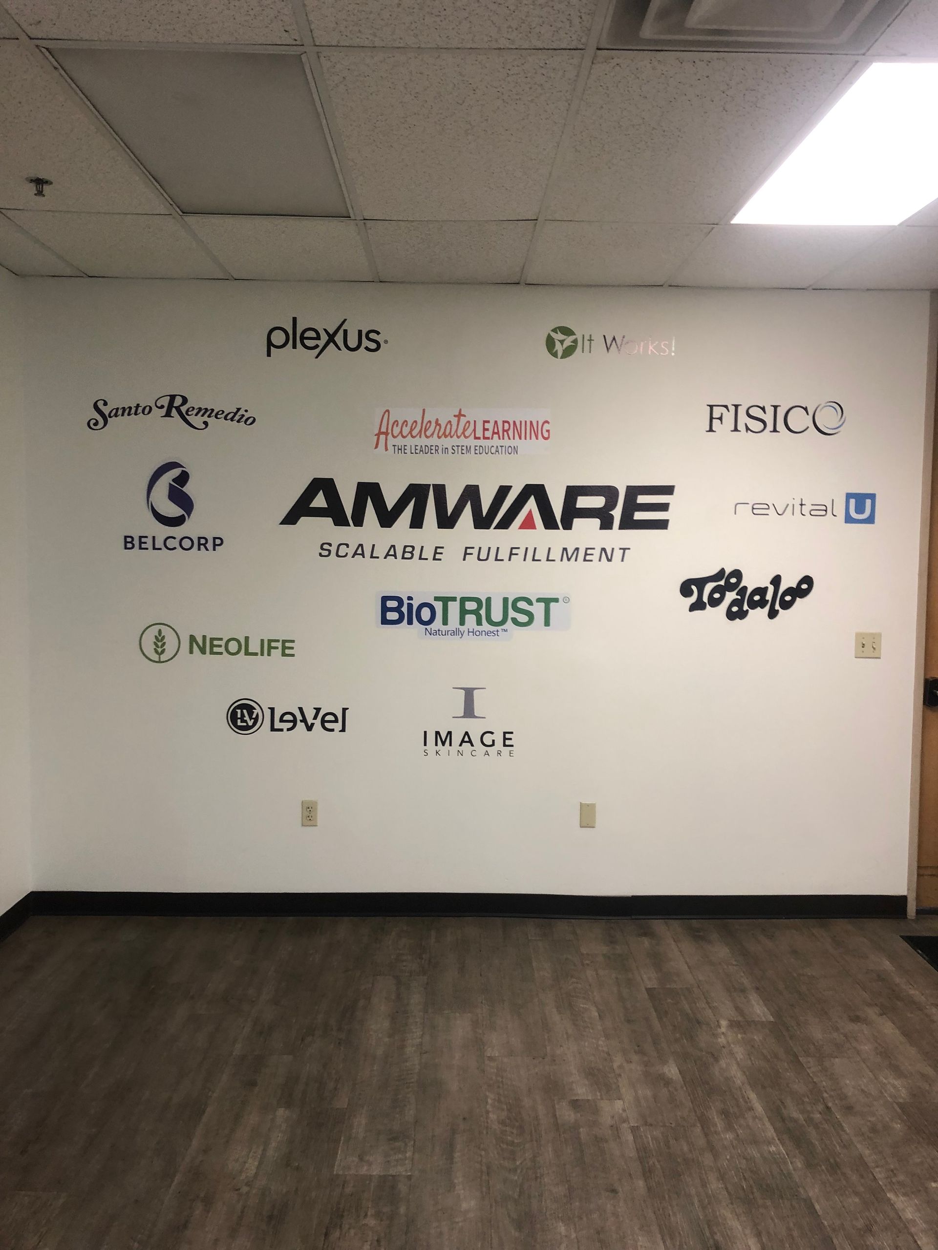 Office wall with multiple company logos and a dark wood floor in front