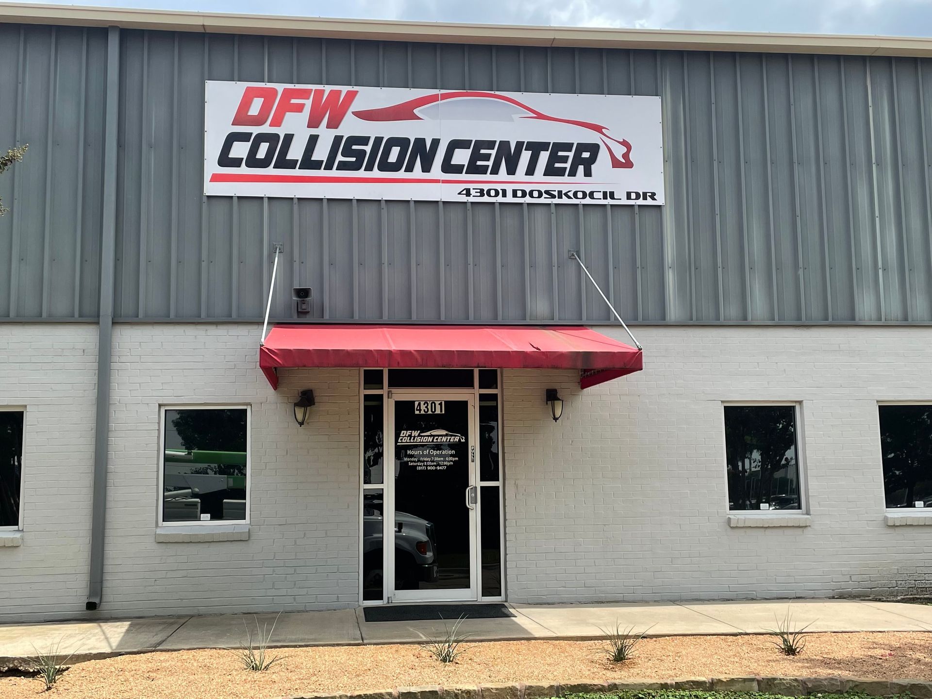 Front exterior of New Collision Center building with red awning and gray siding