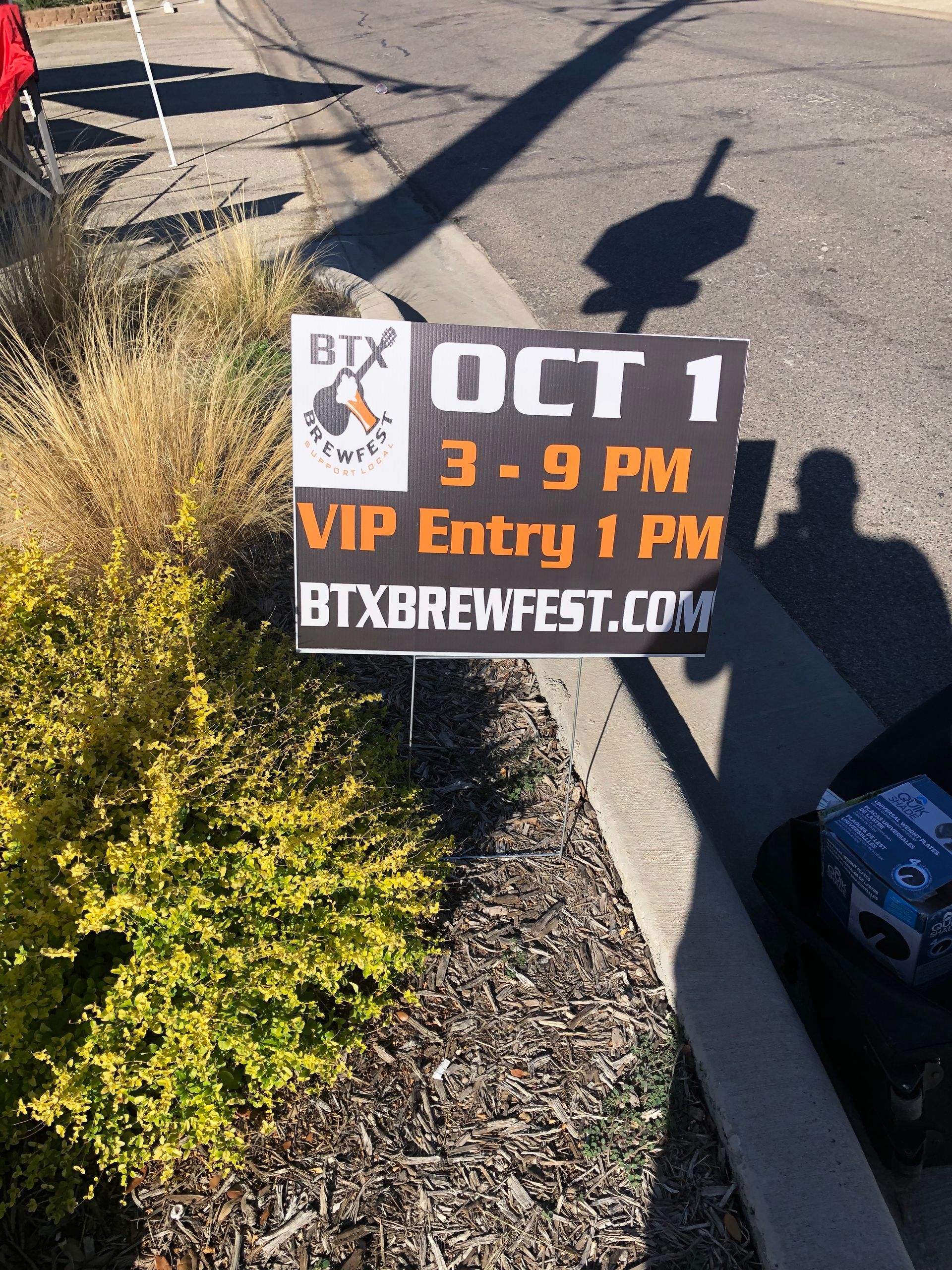 Yard sign advertising BTX Brewfest, Oct. 1, 3–9 PM, VIP entry 1 PM, in a landscaped roadside area