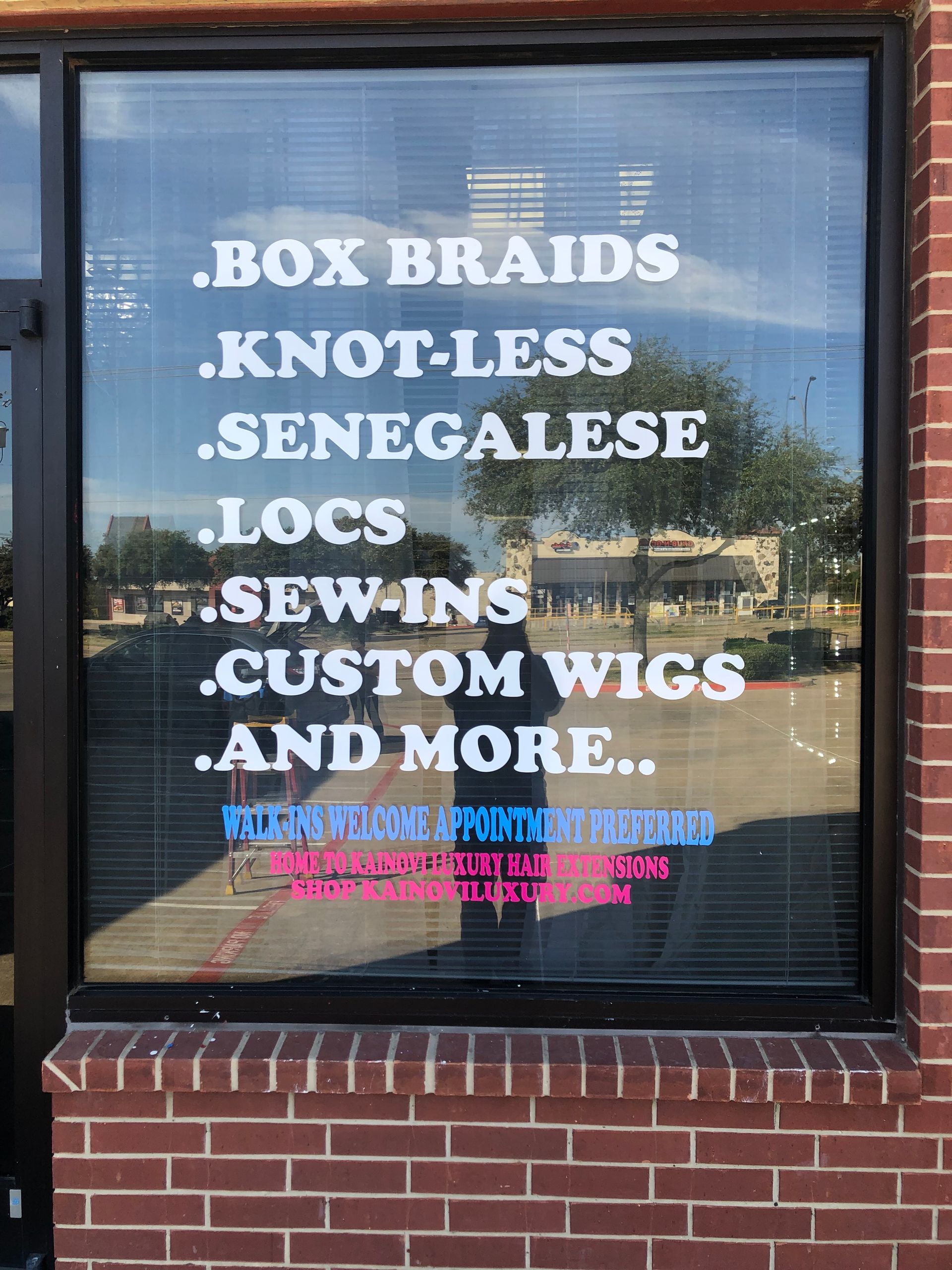 Storefront window sign advertising box braids, knotless, Senegalese locs, sew-ins, custom wigs, and more.