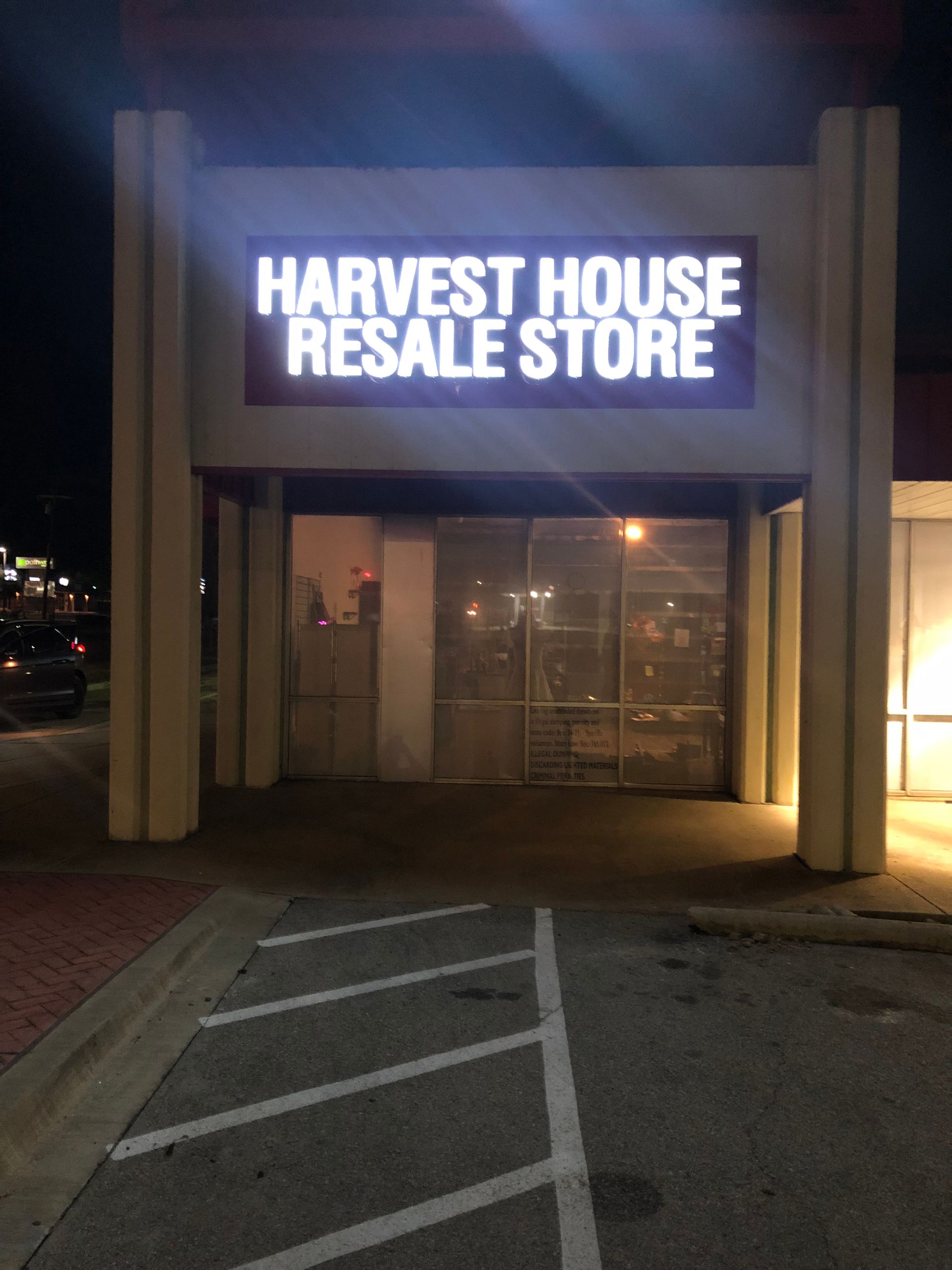 Harvest House Resale Store storefront at night with glowing sign and empty entrance.