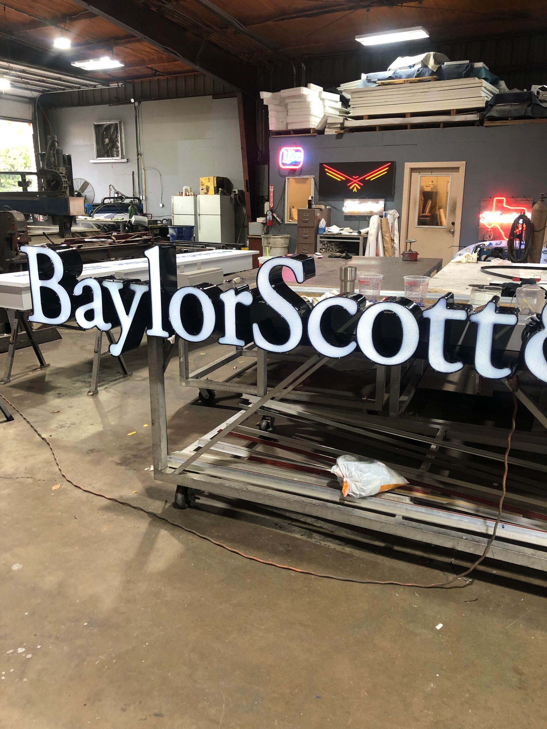 Baylor Scott & White sign in a workshop with metal frames and tools in the background