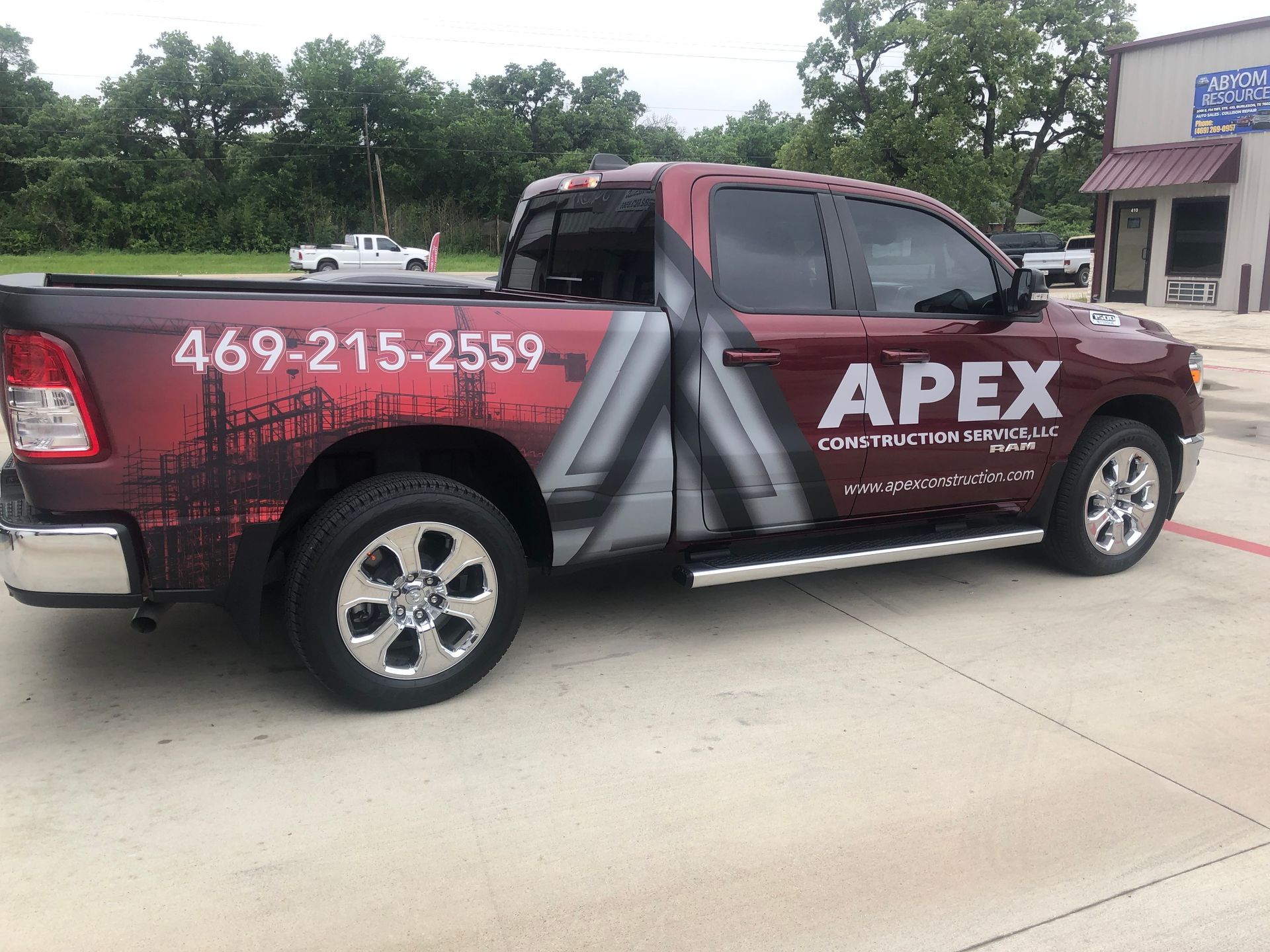 APEX company pickup truck parked outside a storefront, with maroon and gray wrap and phone number 469-215-2559.