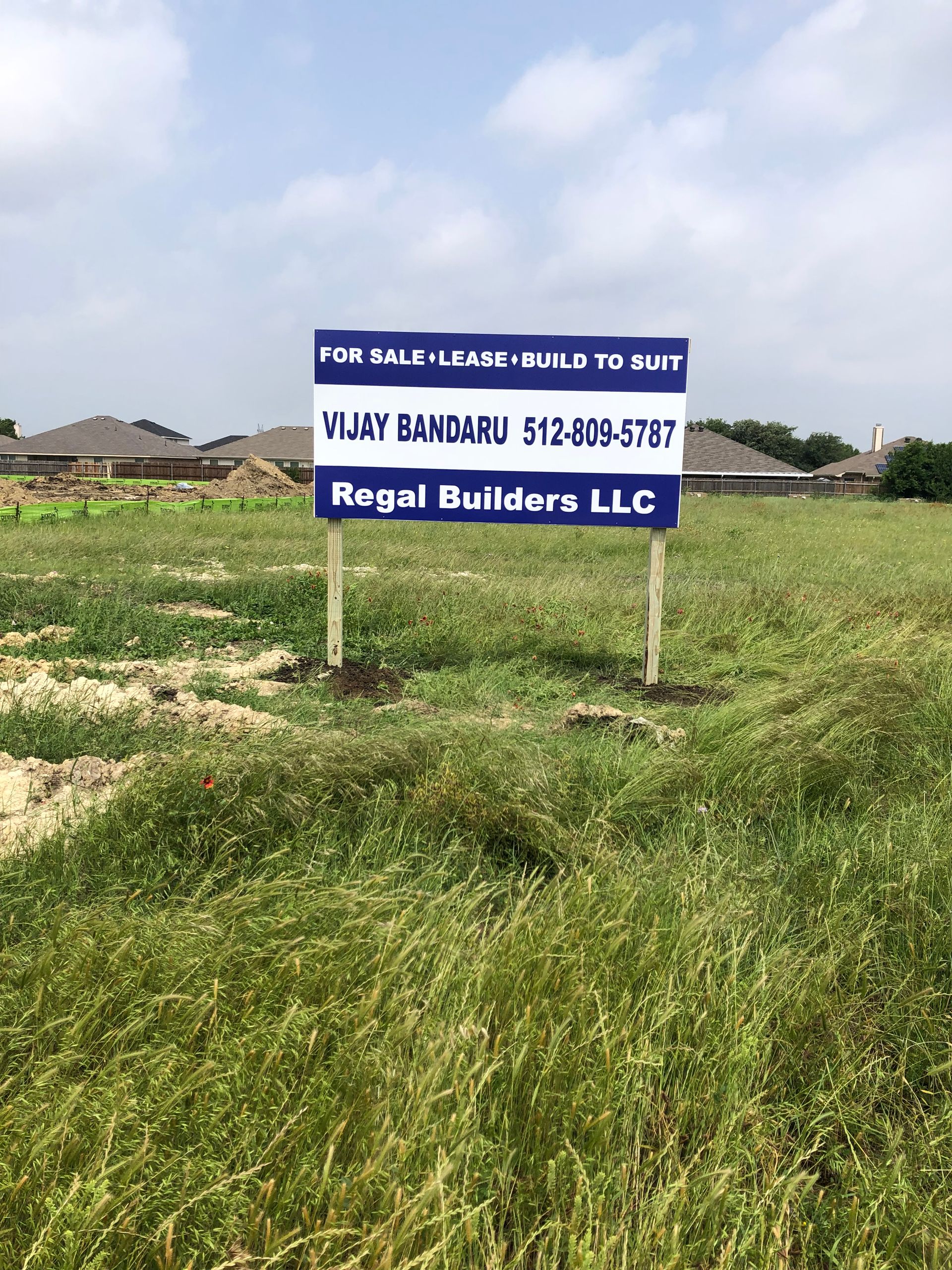 Real estate sign in a grassy field advertising a villa for sale by Regal Builders LLC