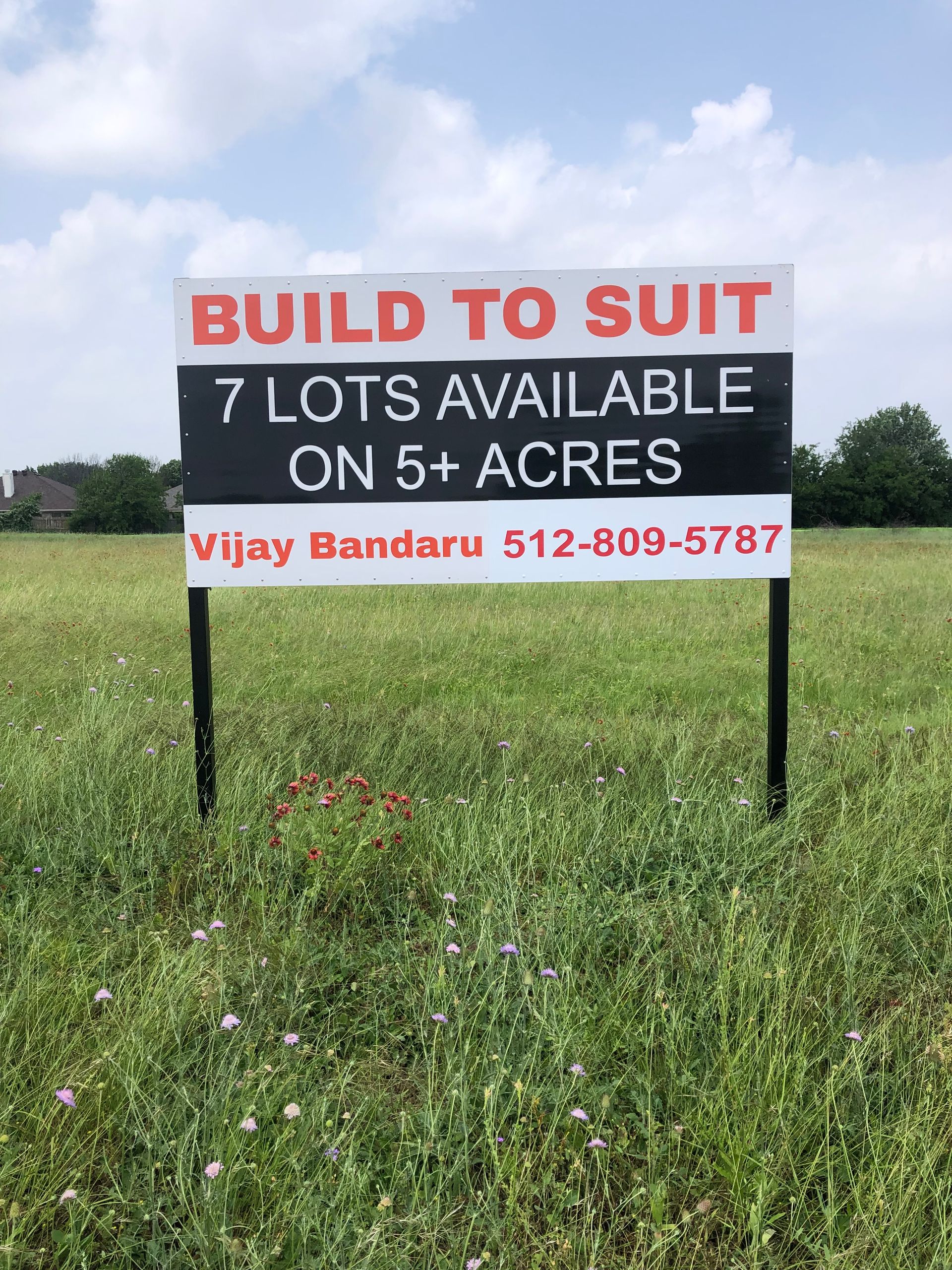 “Build to Suit” sign in a grassy field advertising 7 lots available on 5 acres.