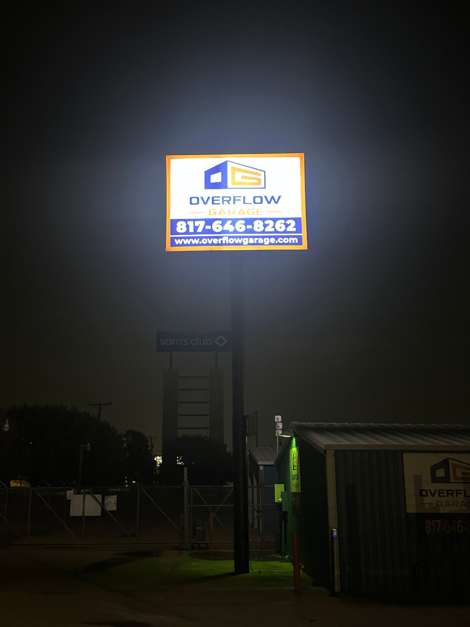 Illuminated Outlaw sign on a tall pole at night above a dark roadside area