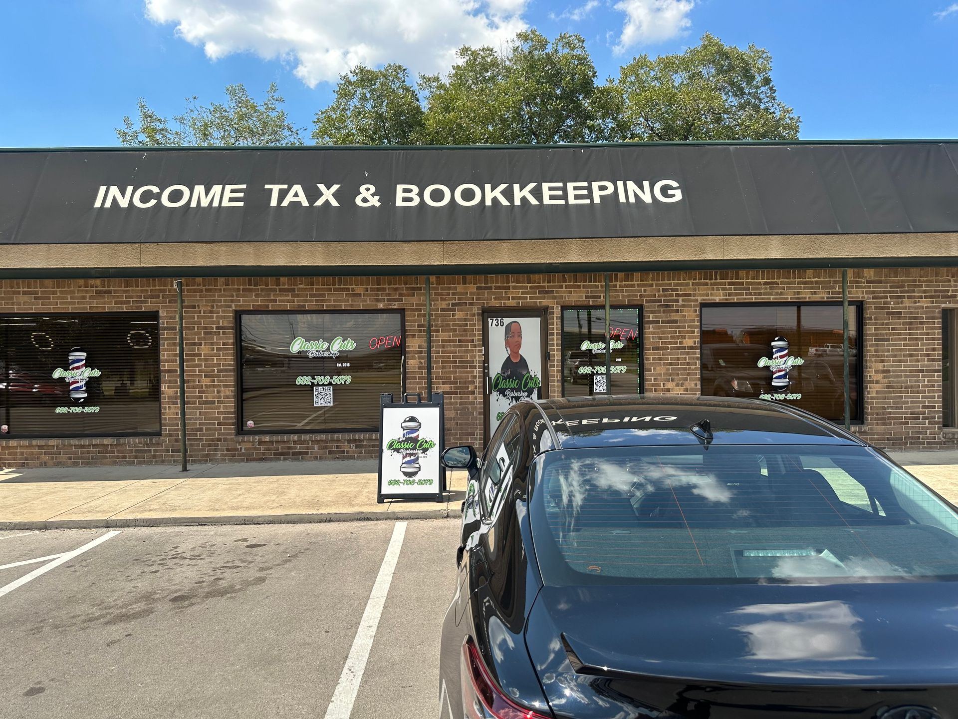 Brick storefront reading “Income Tax & Bookkeeping” with a parked black car in front.