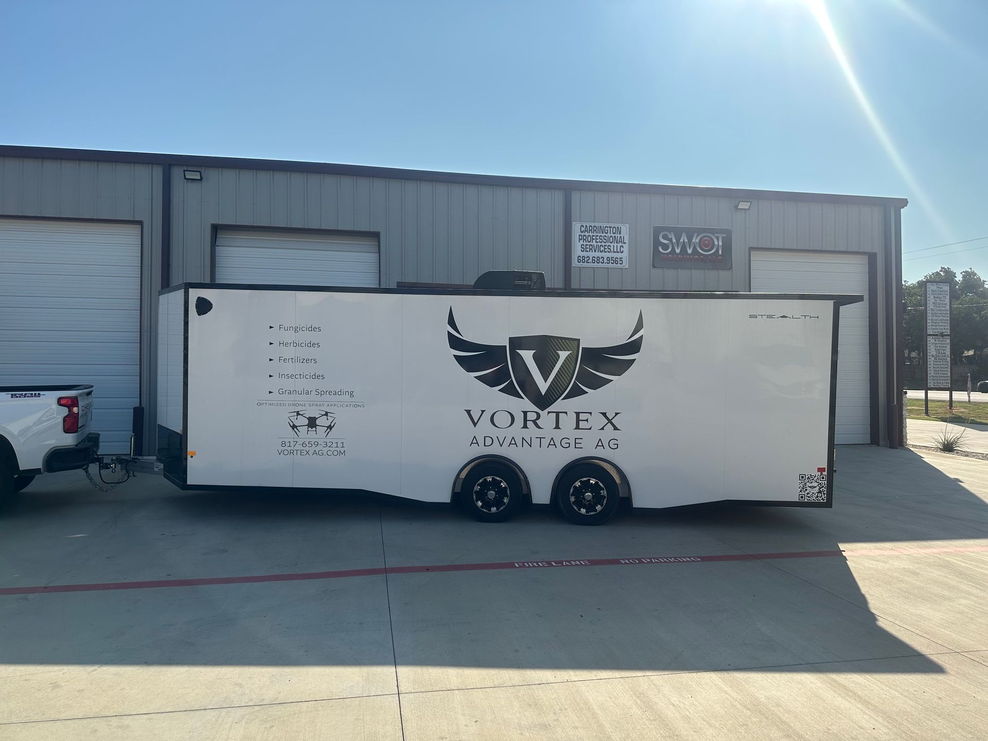 White Vortex trailer parked outside an industrial building on a sunny day