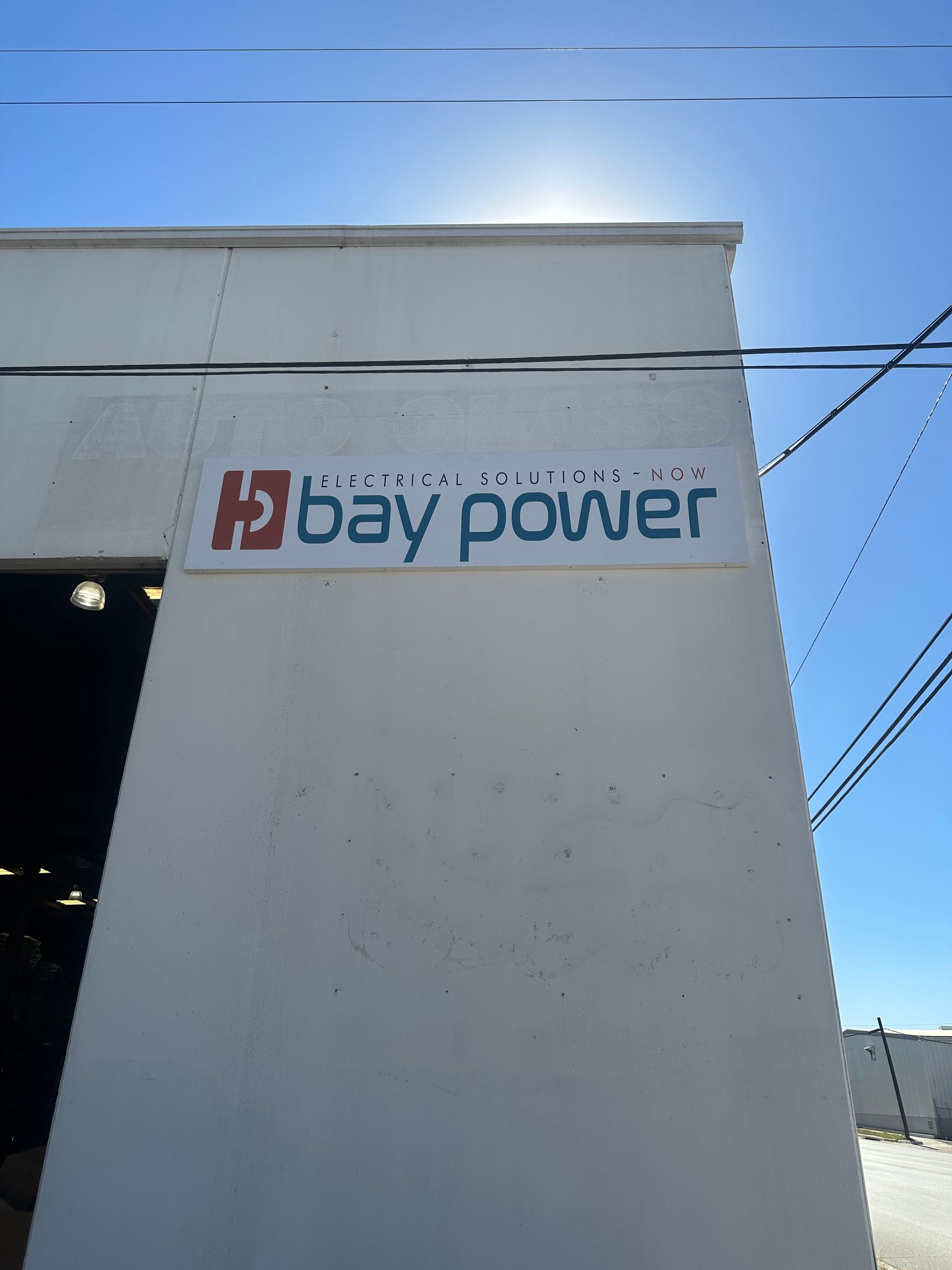 Bay Power sign on a white building under a bright blue sky