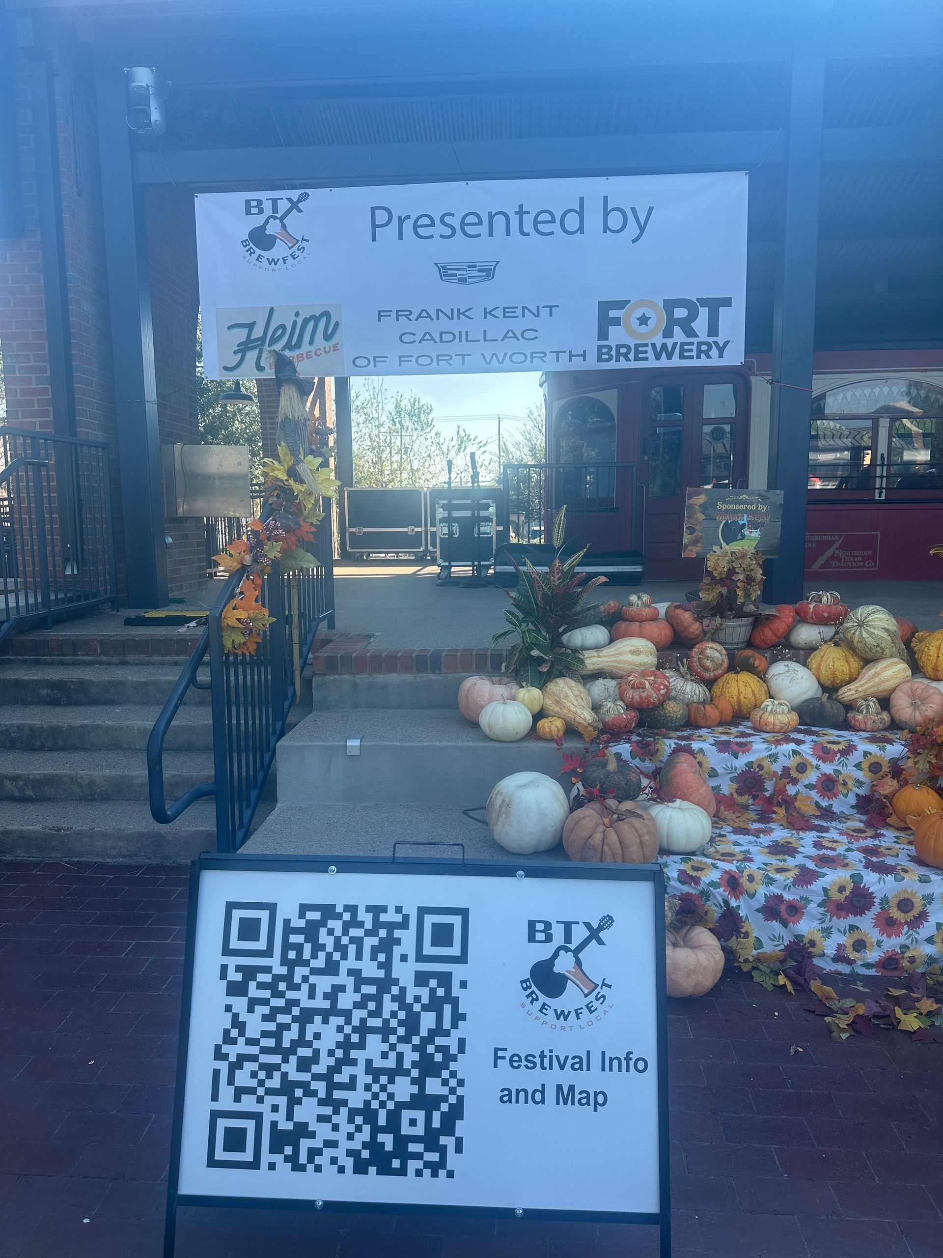 Festival booth with banner, colorful produce display, and QR code sign for the event app.
