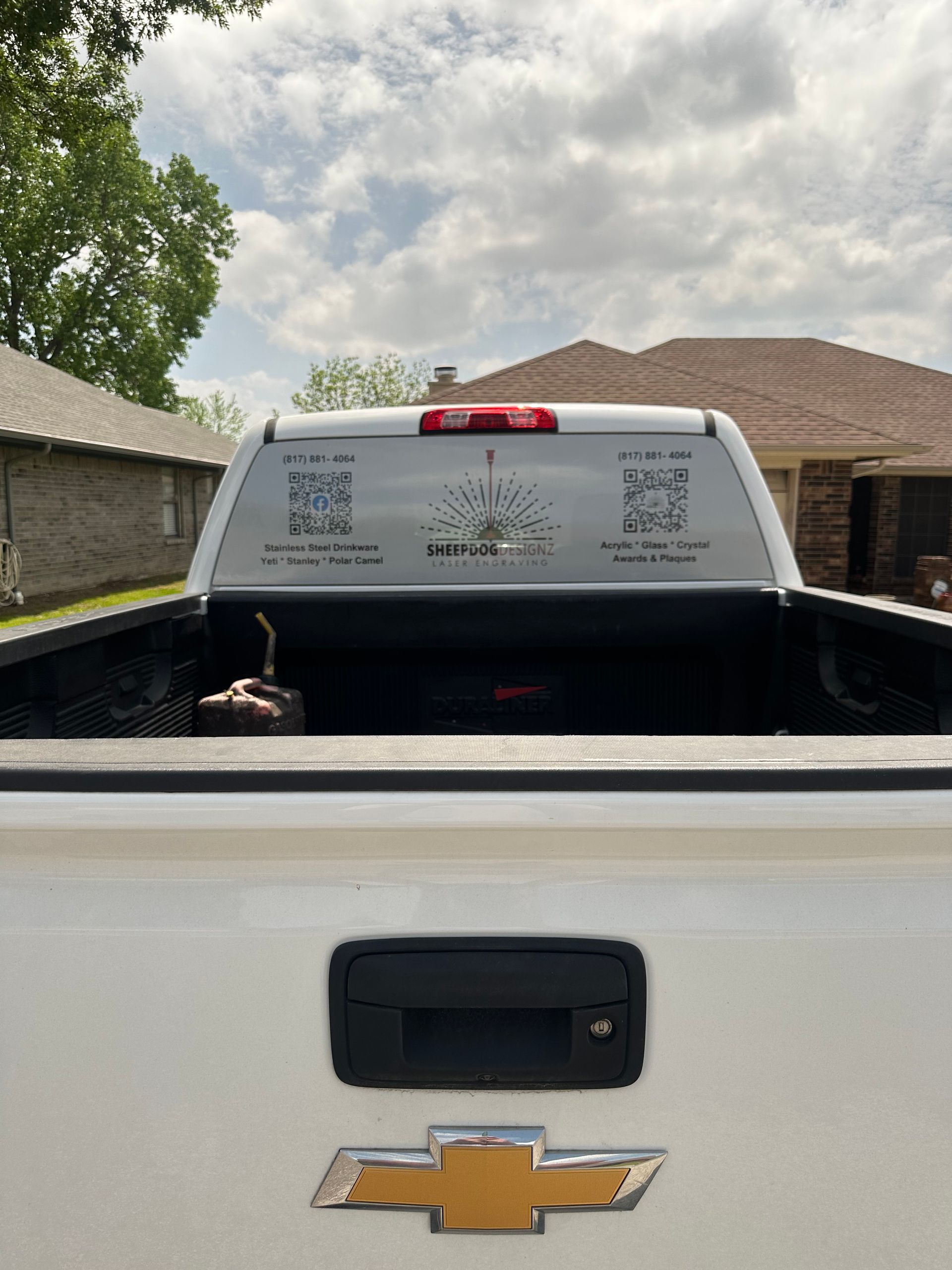 Pickup truck tailgate with gold Chevrolet emblem, viewed from behind in a driveway.