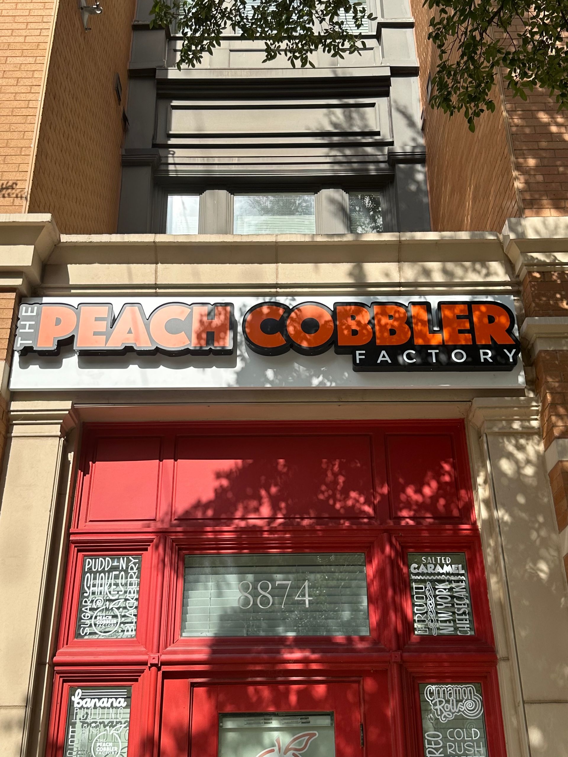 Peach Cobbler Factory storefront with red door and brick facade