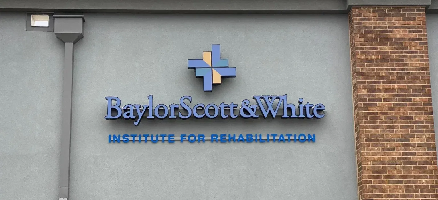 Baylor Scott & White Institute for Rehabilitation sign on a gray building wall
