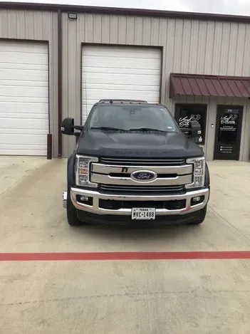 Black Ford pickup parked in front of a garage and office building