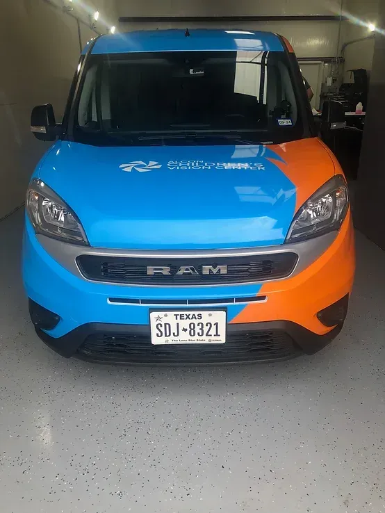 Blue and orange RAM van parked in a garage, front view with license plate visible.