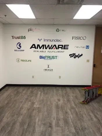 Office wall with multiple company logos and a shopping cart in the corner
