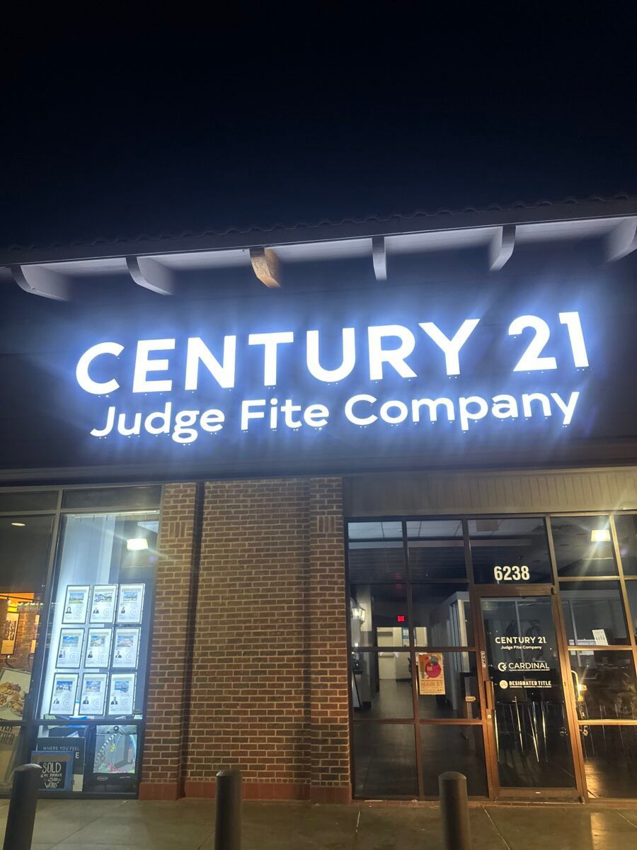 Century 21 Judge Fite Company storefront at night with illuminated sign and glass entrance.