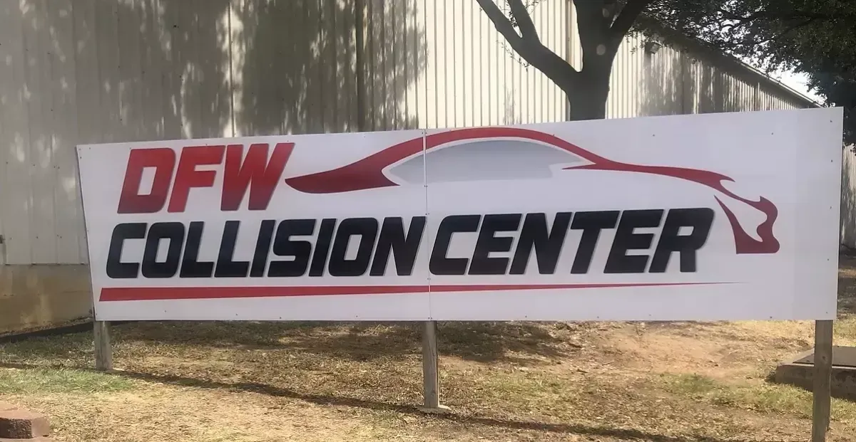 DFW Collision Center sign with red and black text on a white banner outdoors.