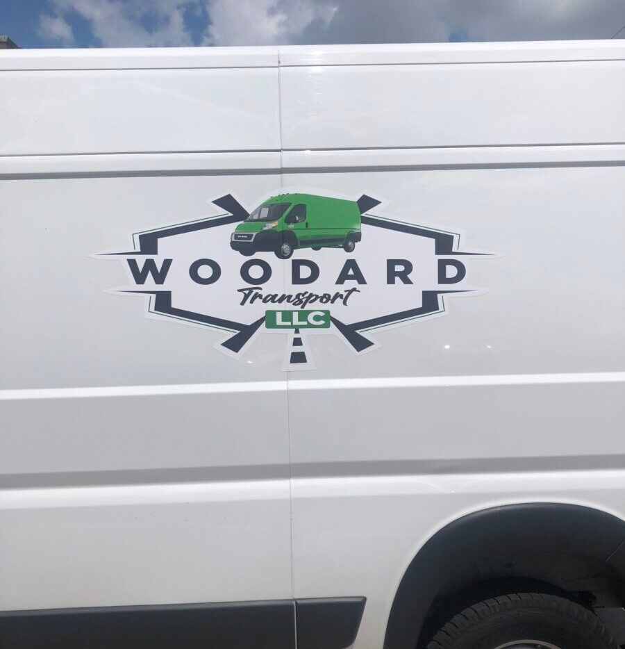 White work van with a “WOOODARD Transportation LLC” logo and green truck graphic on the side.