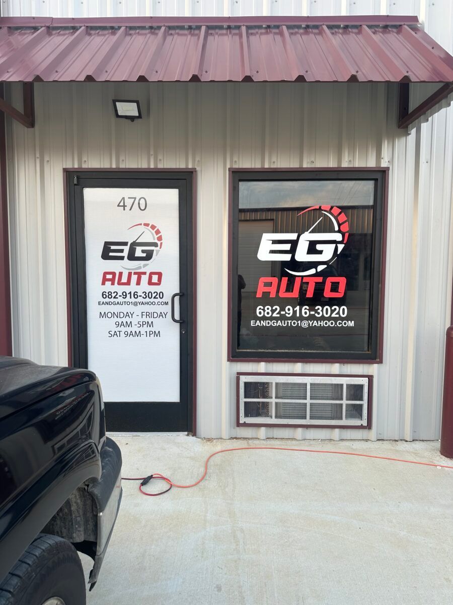 EG Auto storefront with white door, black window sign, and maroon metal awning.