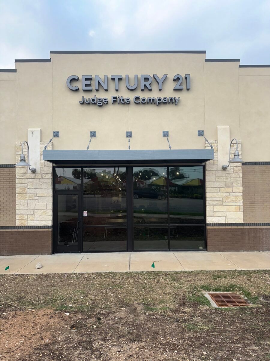Century 21 office storefront with glass doors and tan stone facade