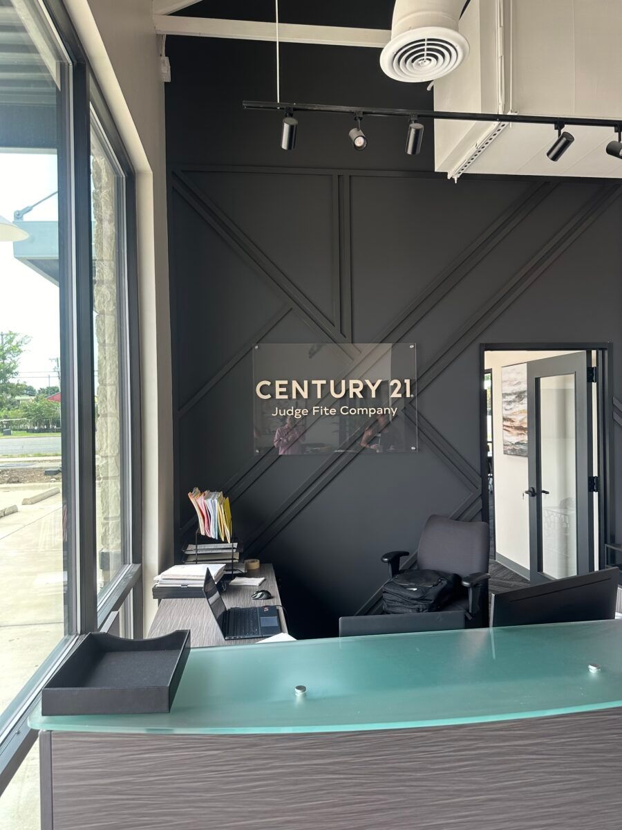 Century 21 real estate office reception desk with black walls and teal counter