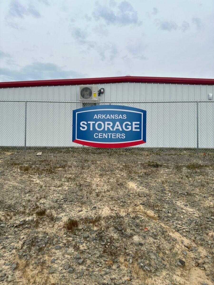 Arkansas Storage Centers building with blue sign and red roof behind a gravel lot