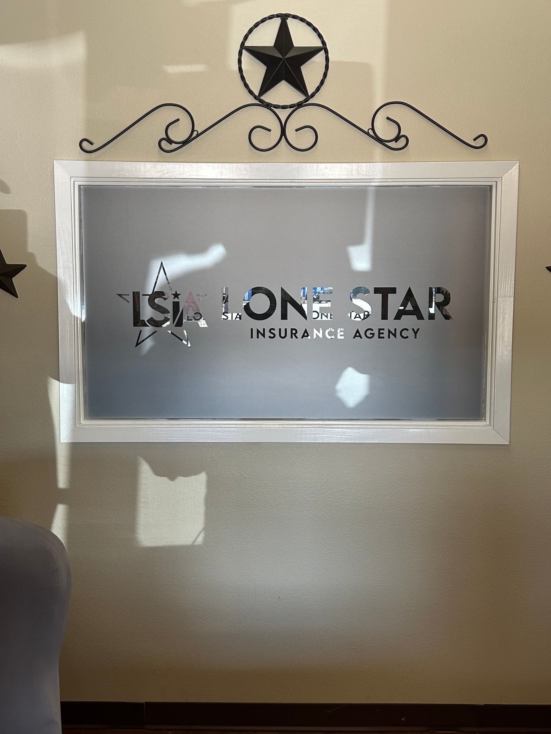 Wall sign for Lone Star Insurance Agency with a star emblem and decorative black swirls on a beige wall
