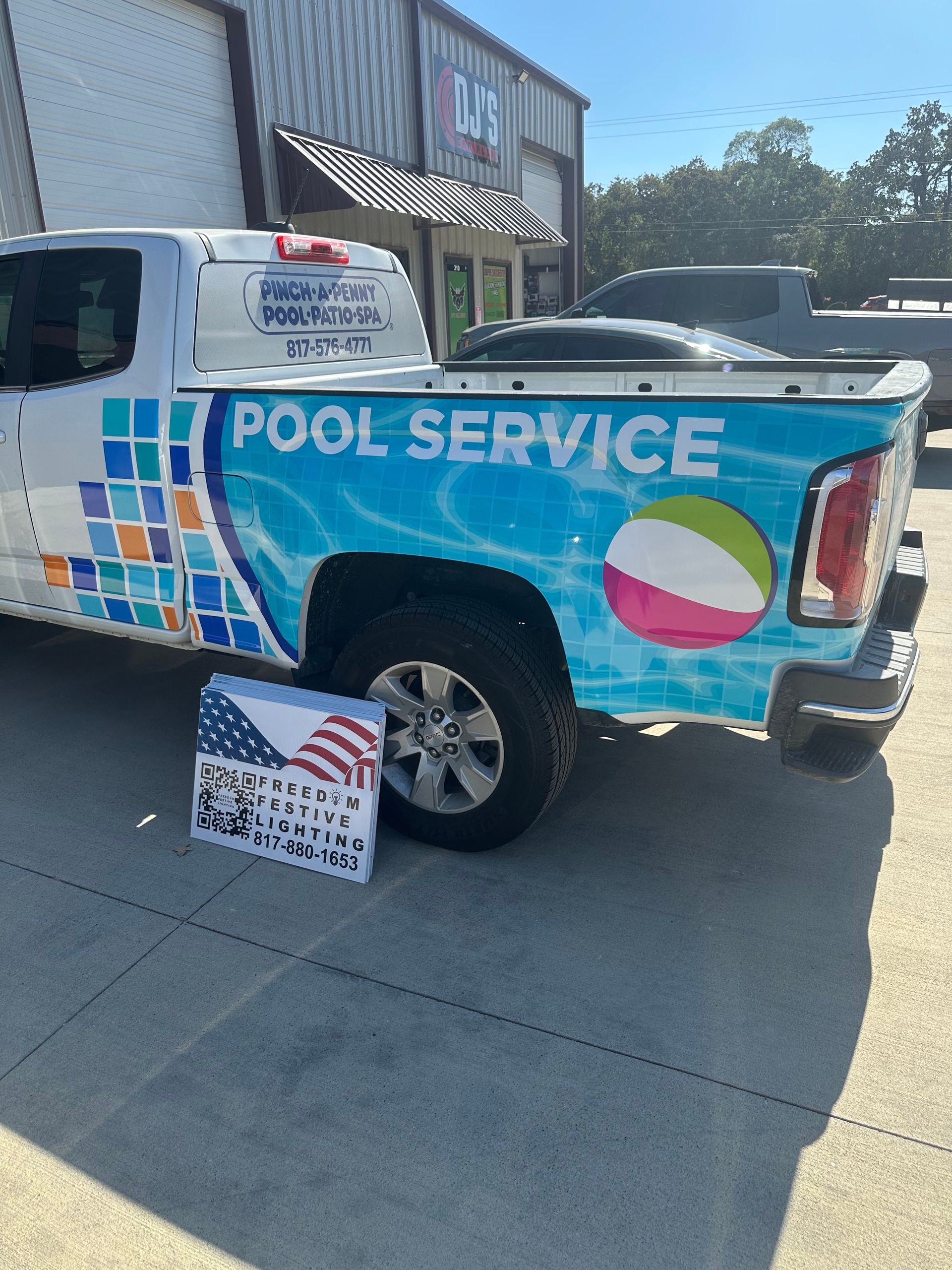 Pool service pickup truck with colorful wrap parked outside a storefront.