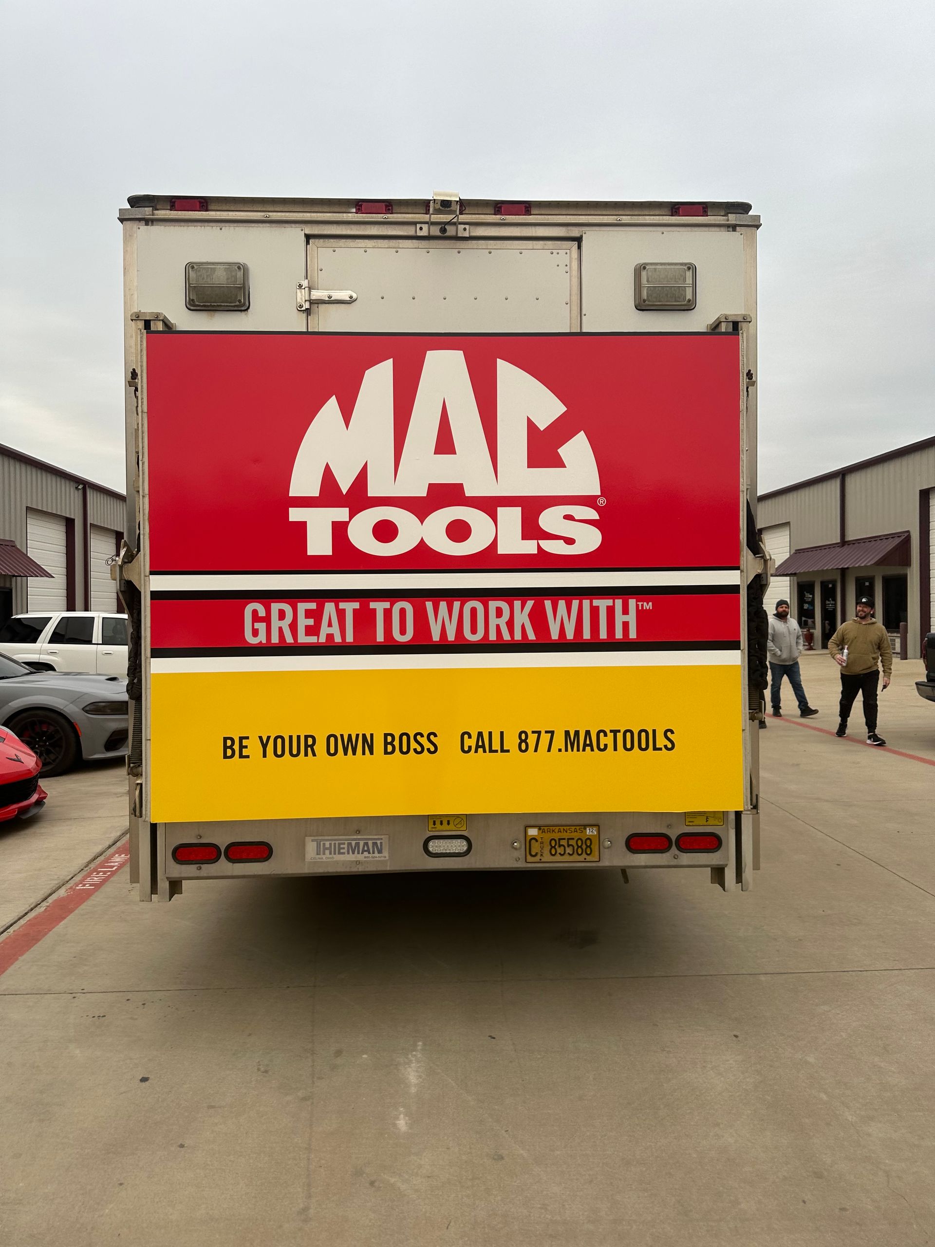 Red Mac Tools truck parked on a street, rear doors showing “Great to Work With” slogan.