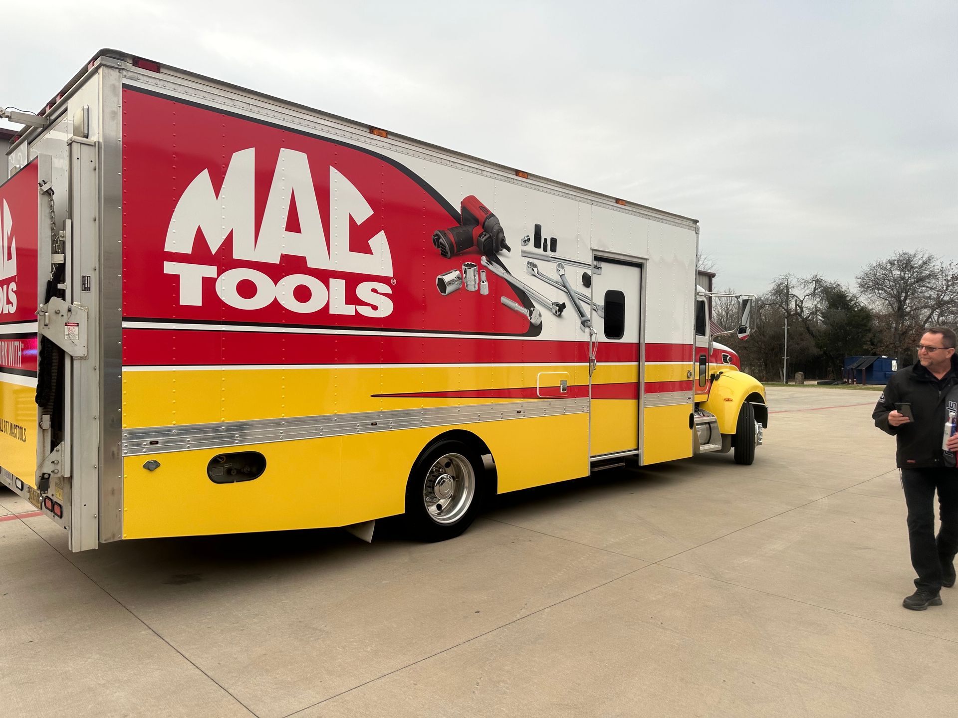 MAN Tools truck with red, white, and yellow branding parked on a concrete lot; person standing nearby