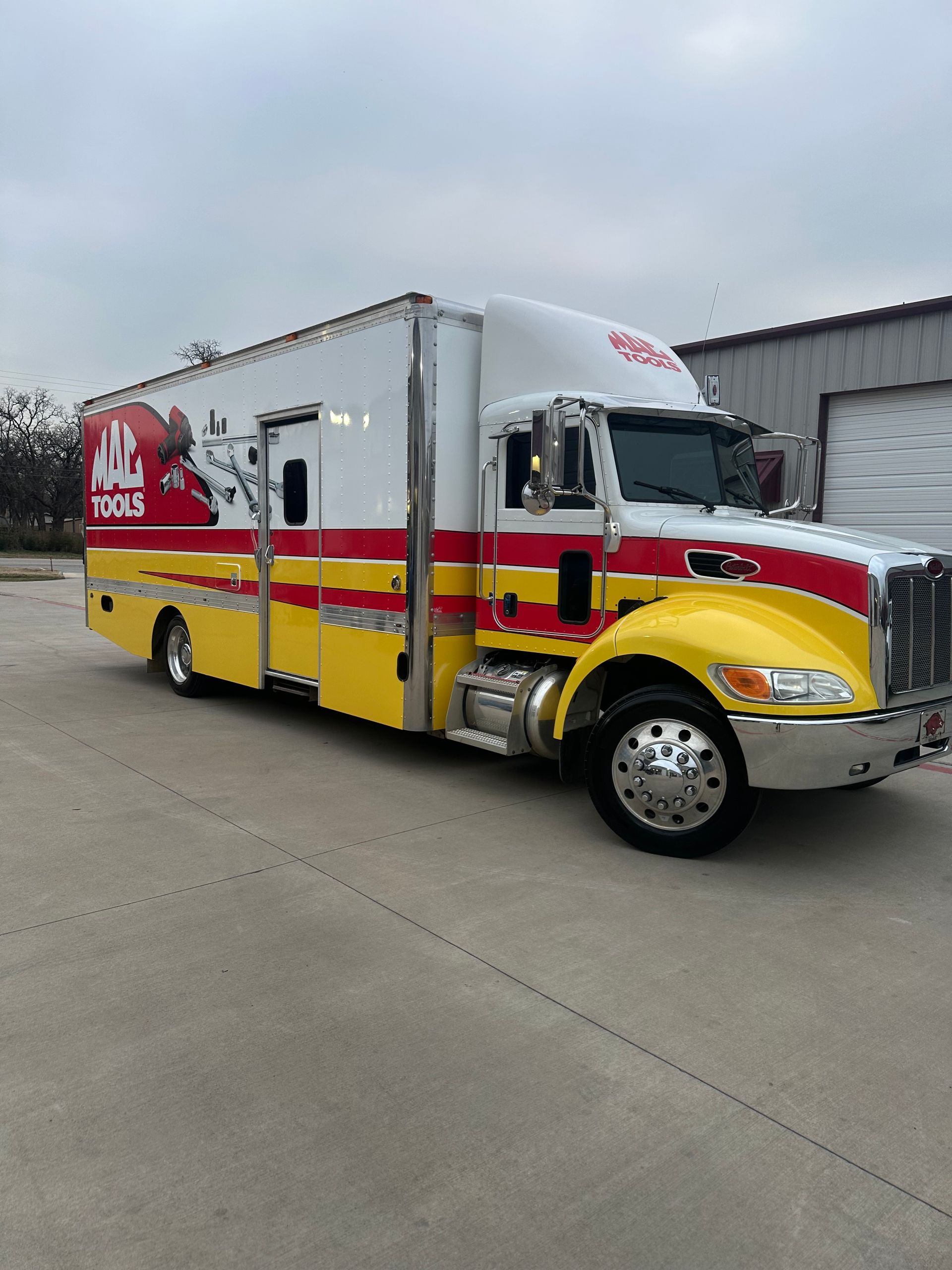 Red and yellow H&E moving truck parked on a concrete lot